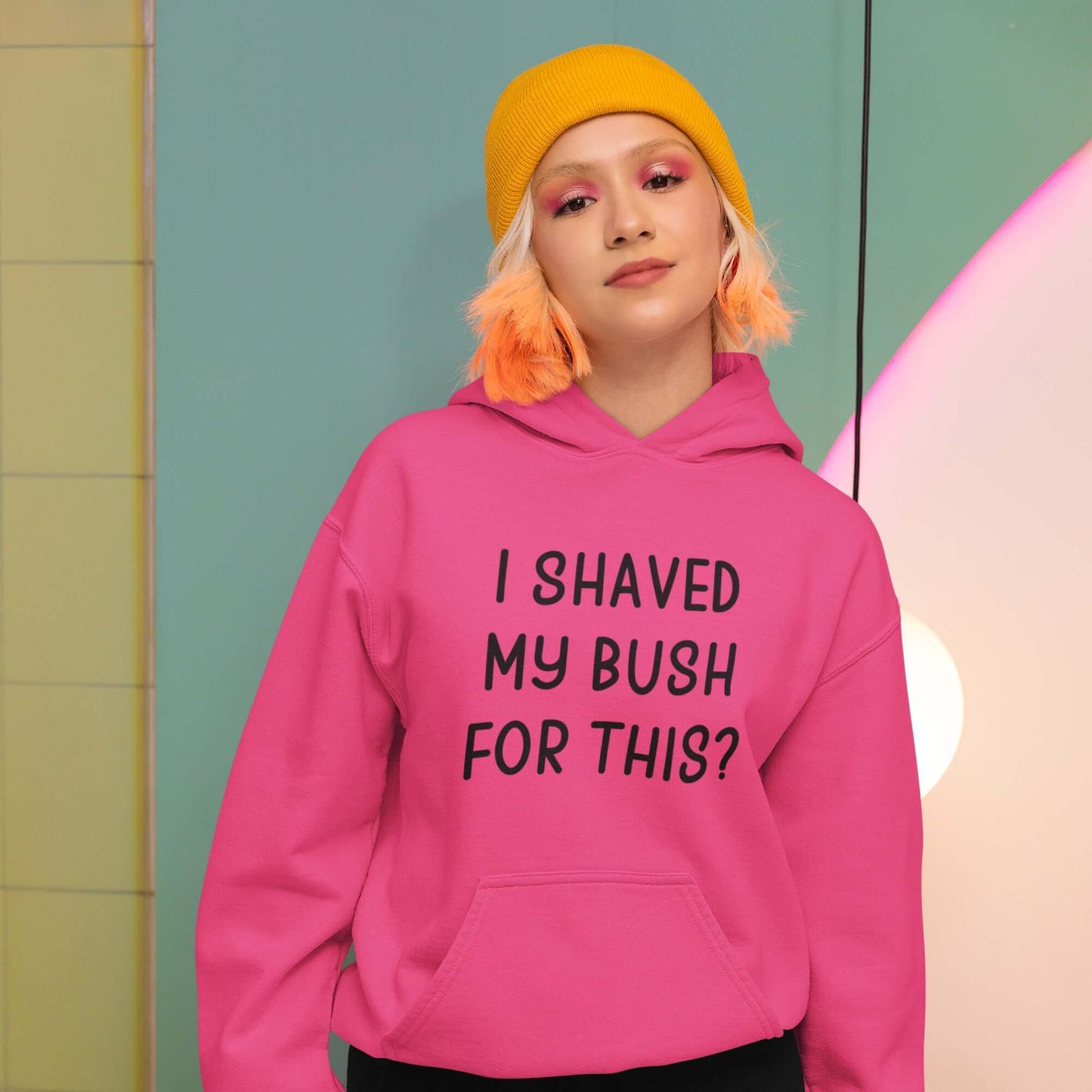 Woman wearing a heliconia pink hoodie sweatshirt with the phrase I shaved my bush for this? printed on the front.