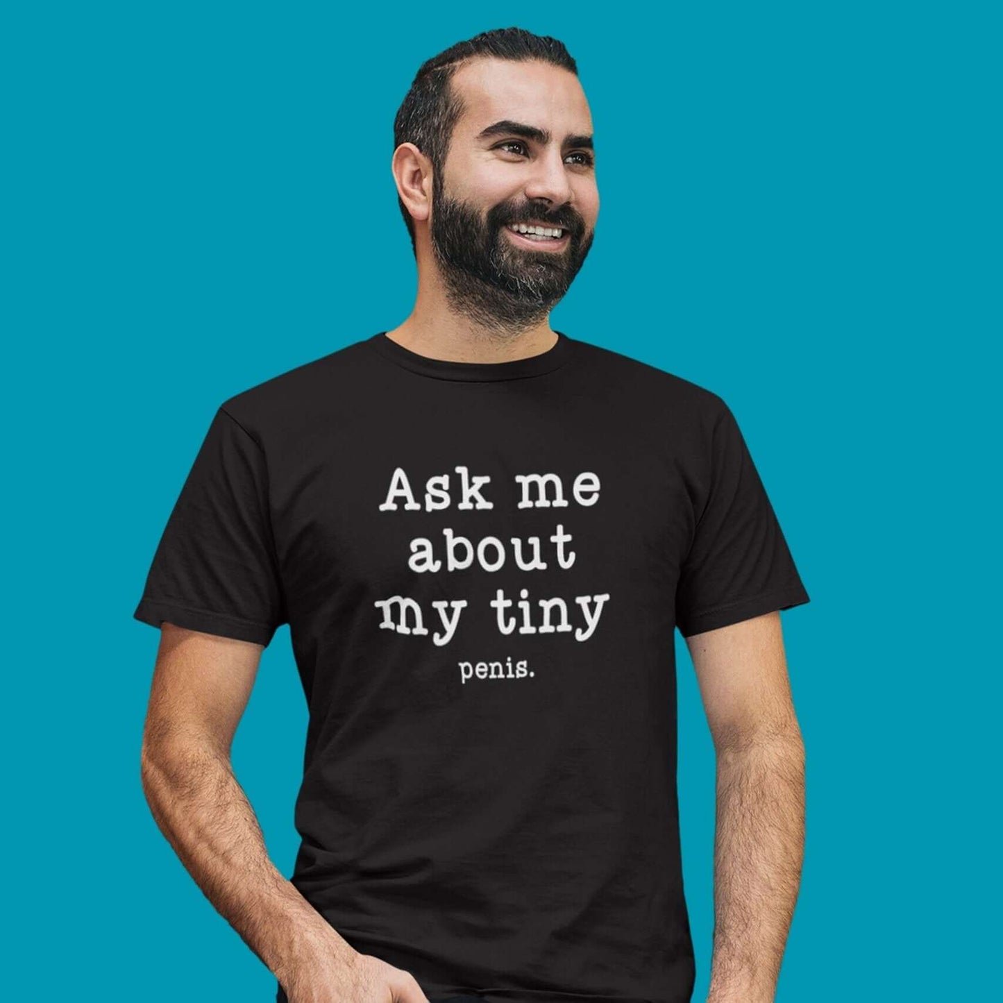 Man wearing a black t-shirt with the phrase Ask me about my tiny penis printed on the front. The word penis is much smaller than the rest of the text.