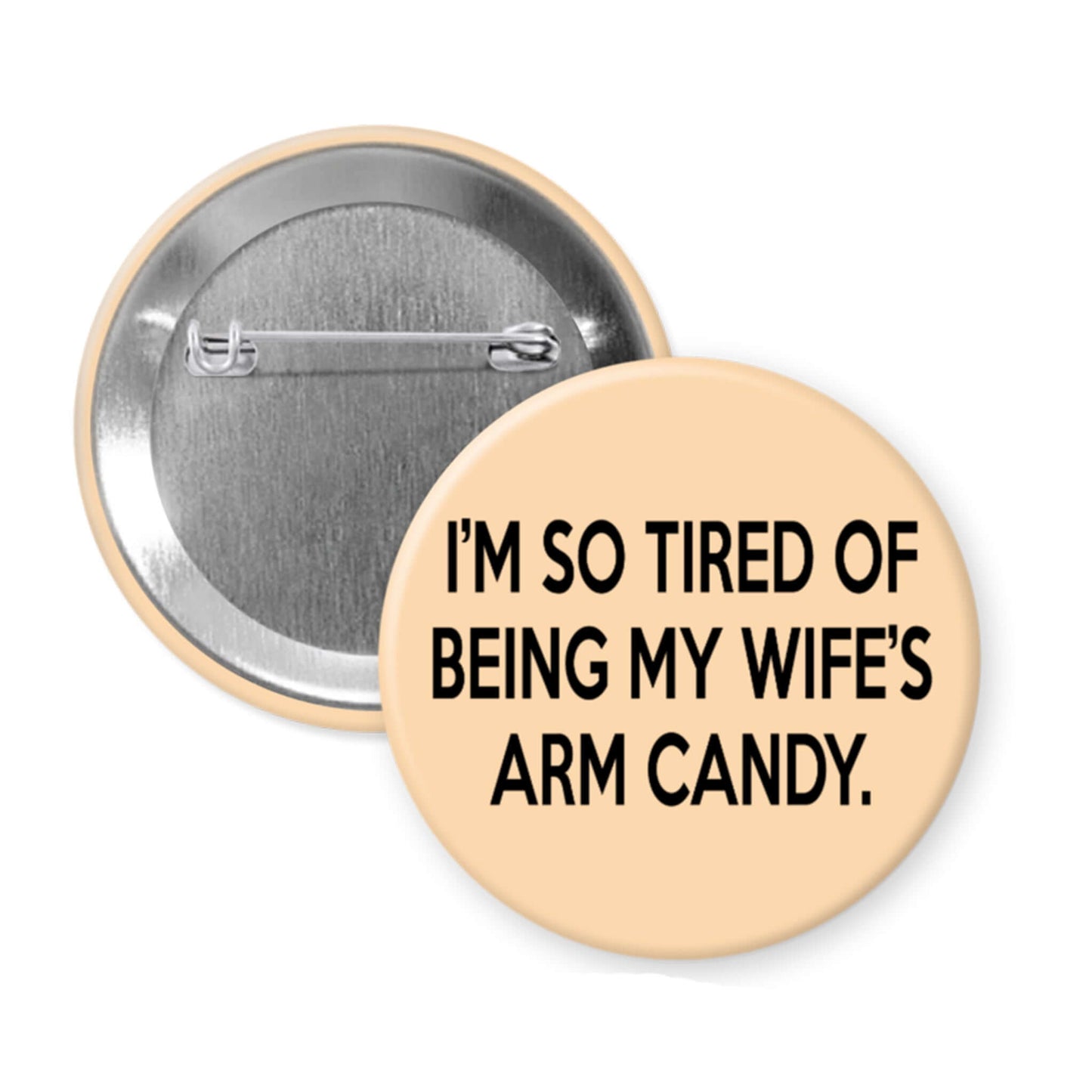 Button badge with text 'I'm so tired of being my wife's arm candy' on a beige background