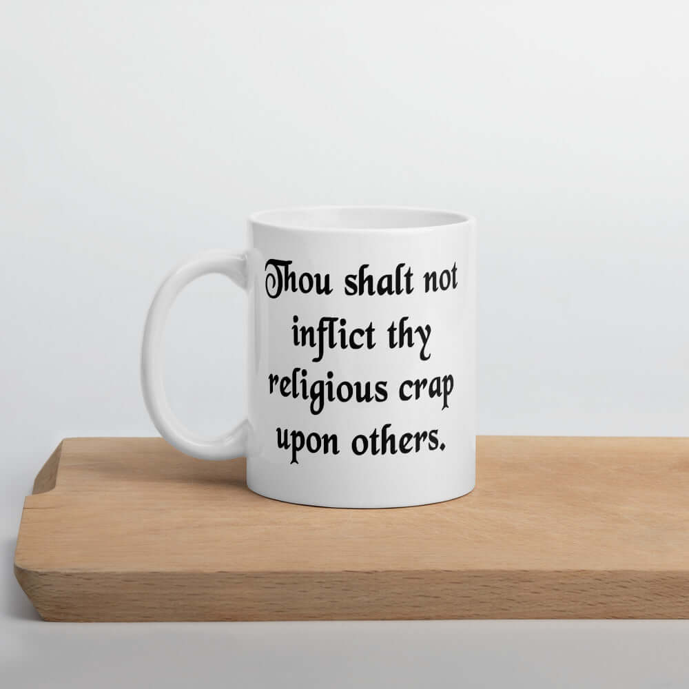 White ceramic coffee mug with the phrase Thou shalt not inflict thy religious crap upon others printed on both sides.
