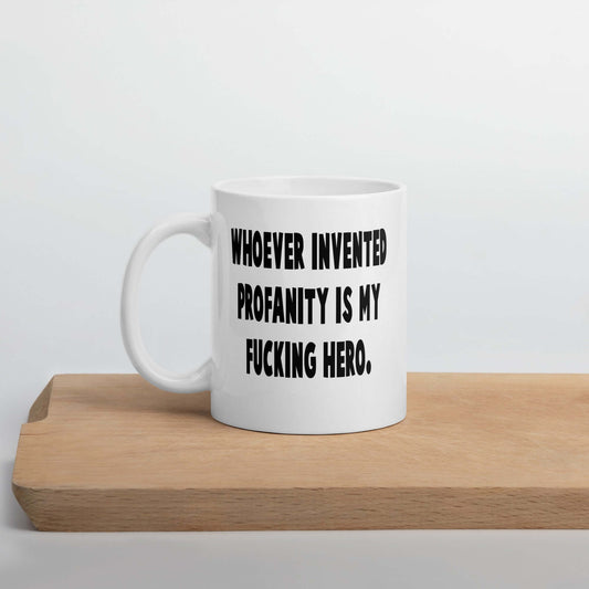White ceramic mug with the phrase Whoever invented profanity is my fucking hero printed on both sides.