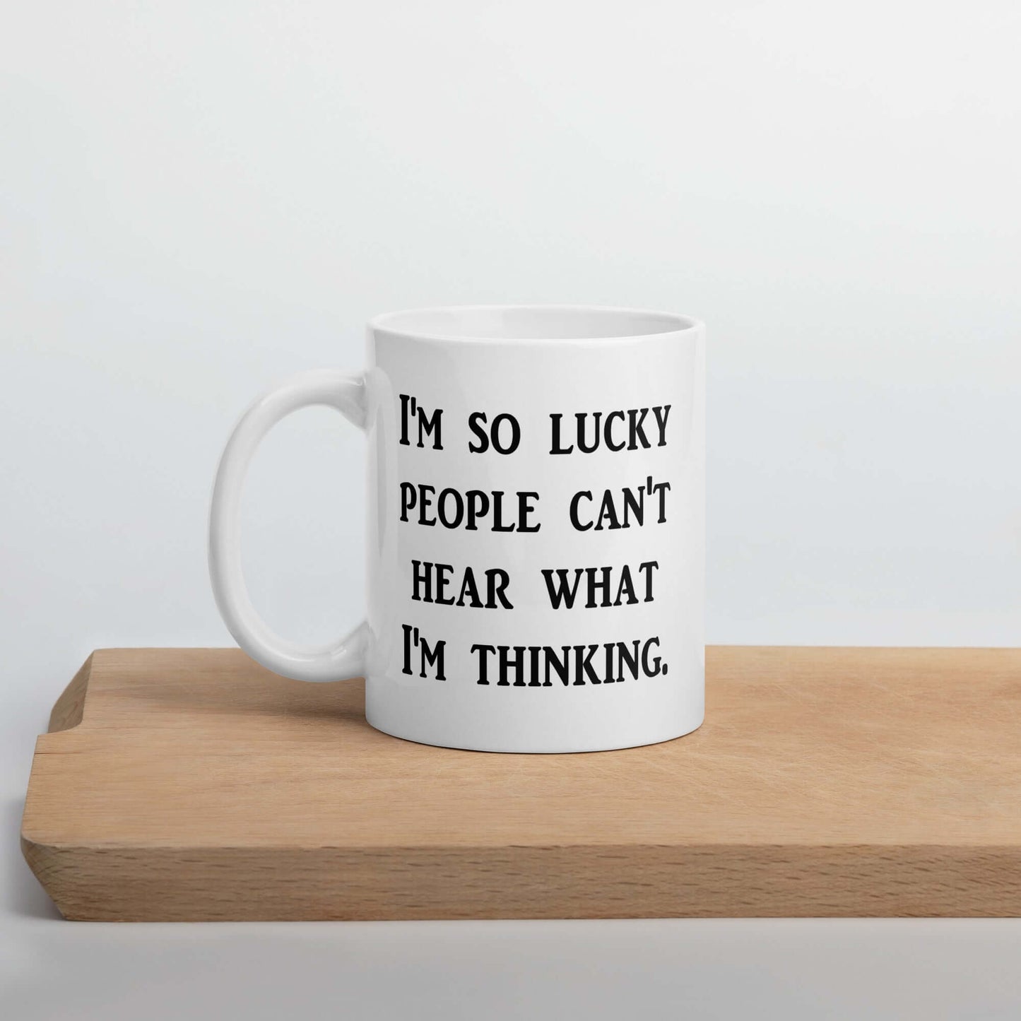 White ceramic mug that has the words I'm so lucky people can't hear what I'm thinking printed on both sides.