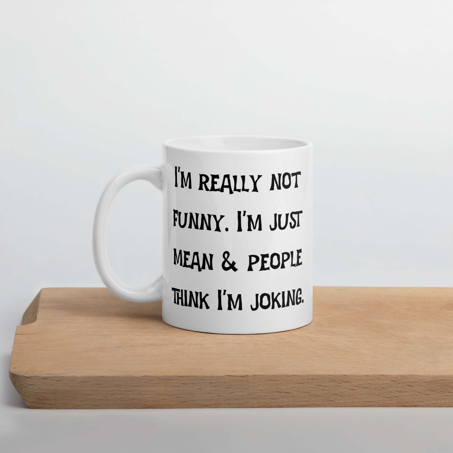White ceramic mug with the phrase I'm really not funny. I'm just mean & people think I'm joking printed on both sides.