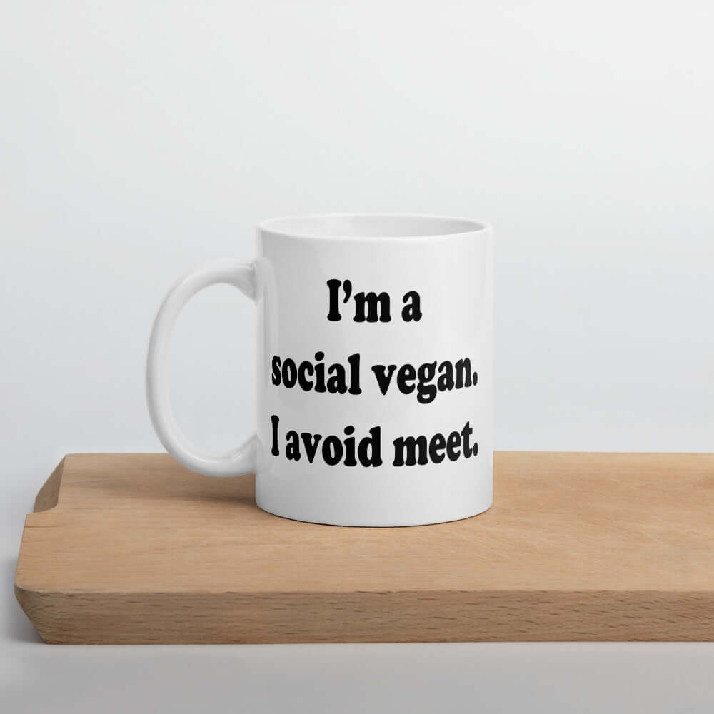 White ceramic coffee mug with the pun phrase I'm a social vegan, I avoid meet printed on both sides.