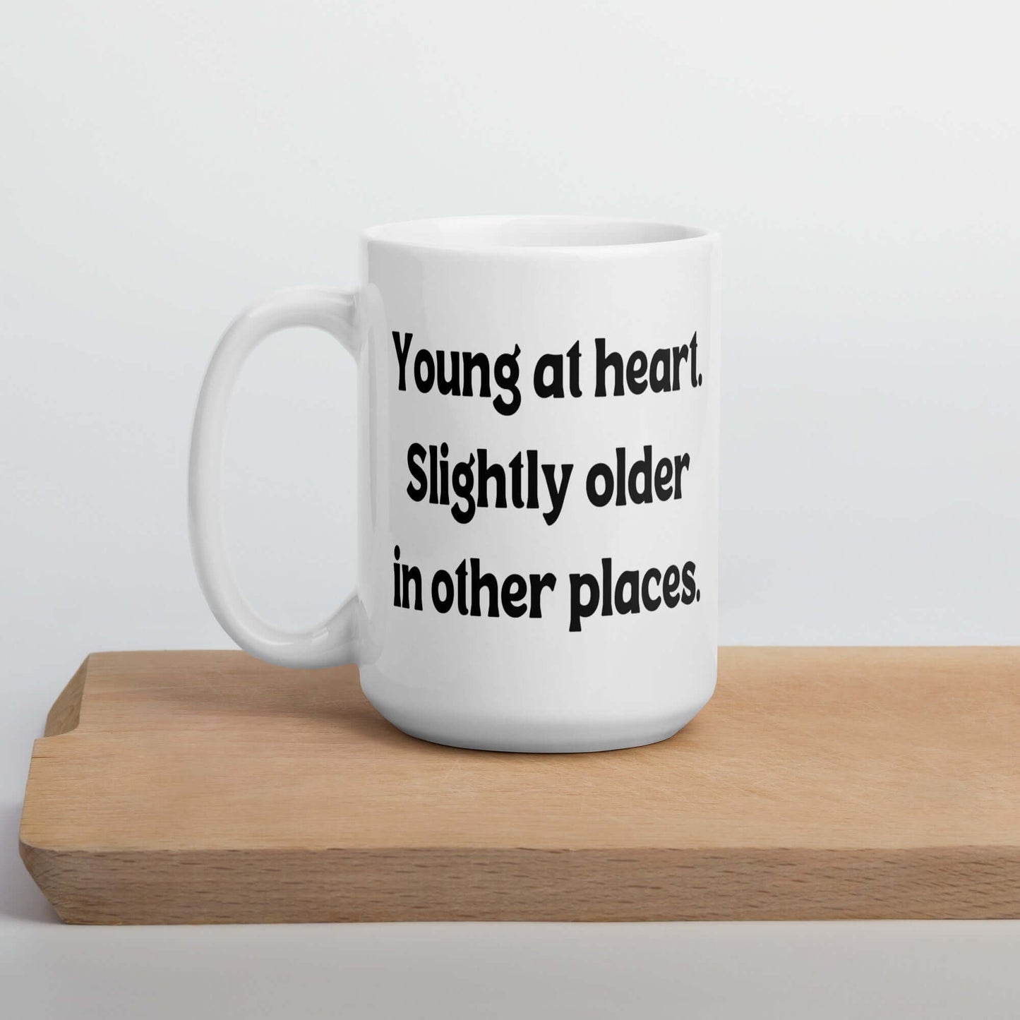 White ceramic mug with the words Young at heart, slightly older in other places printed on both sides.