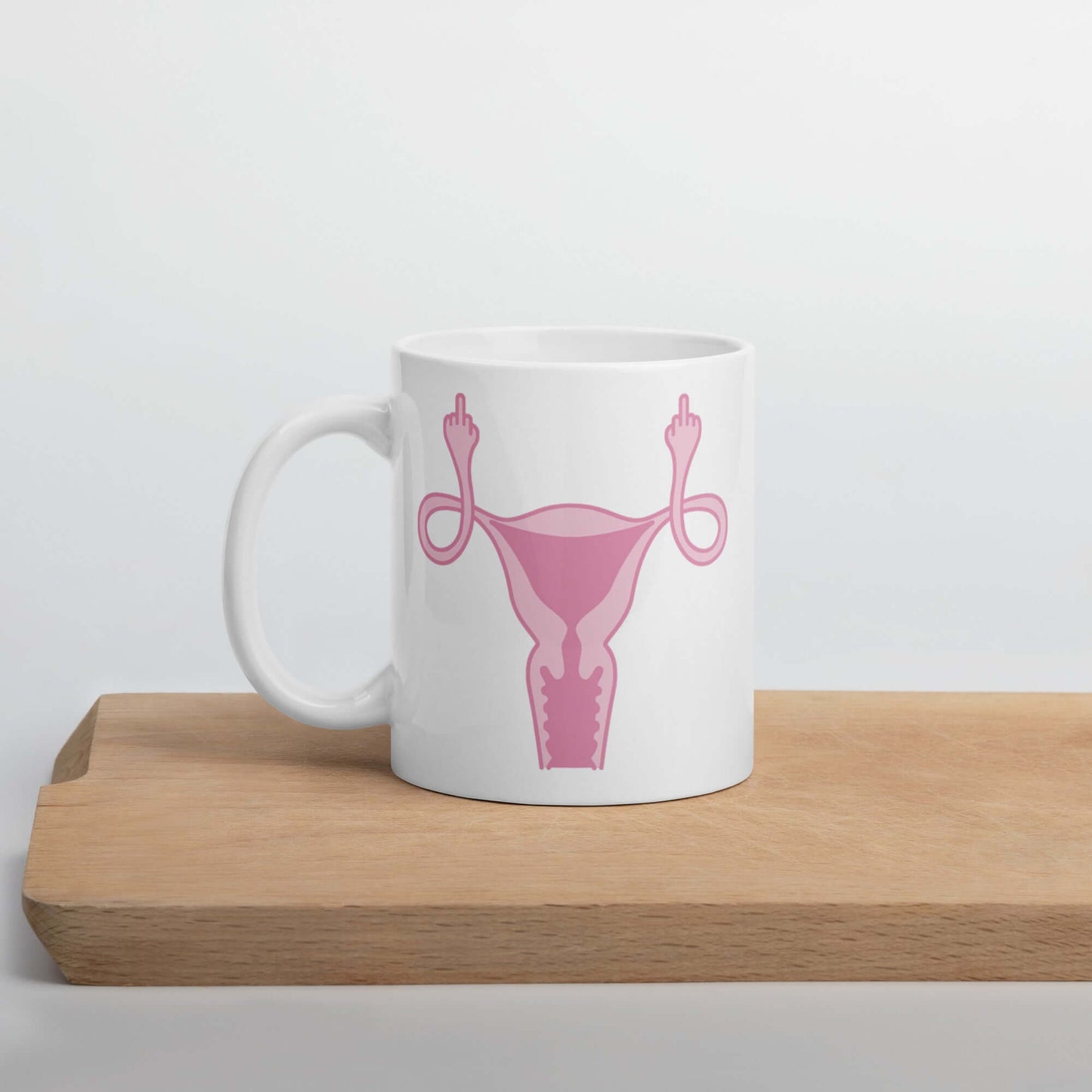 11 ounce white ceramic mug with image of a pink uterus flipping middle finger graphic printed on both sides.