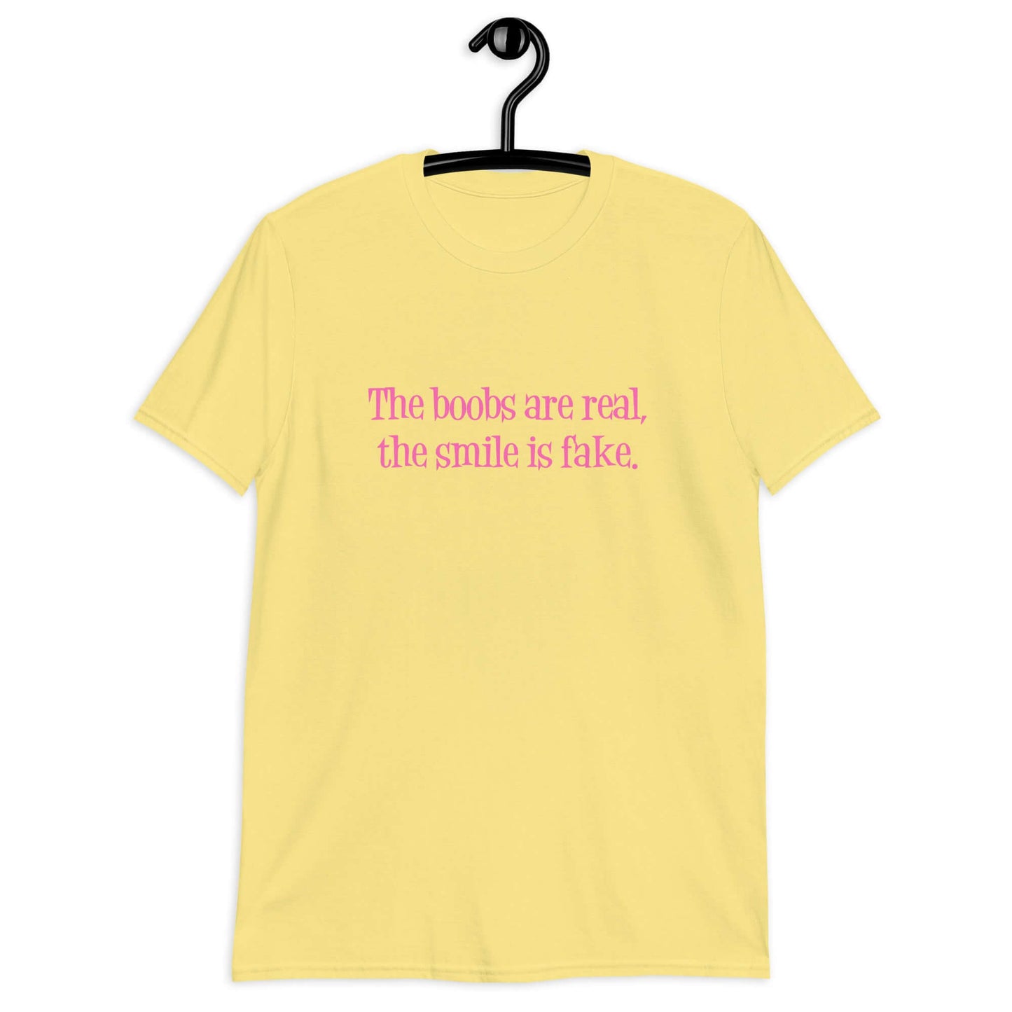 Cornsilk yellow t-shirt with the phrase The boobs are real, the smile is fake printed in pink on the front.
