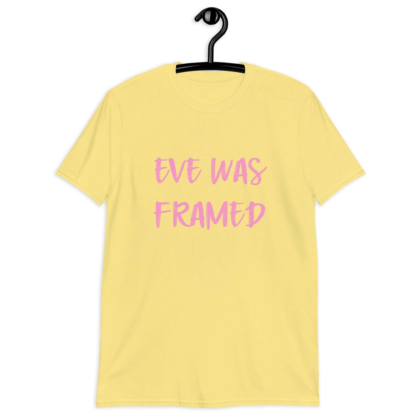 Cornsilk yellow t-shirt with the words Eve was framed printed on the front in pink.