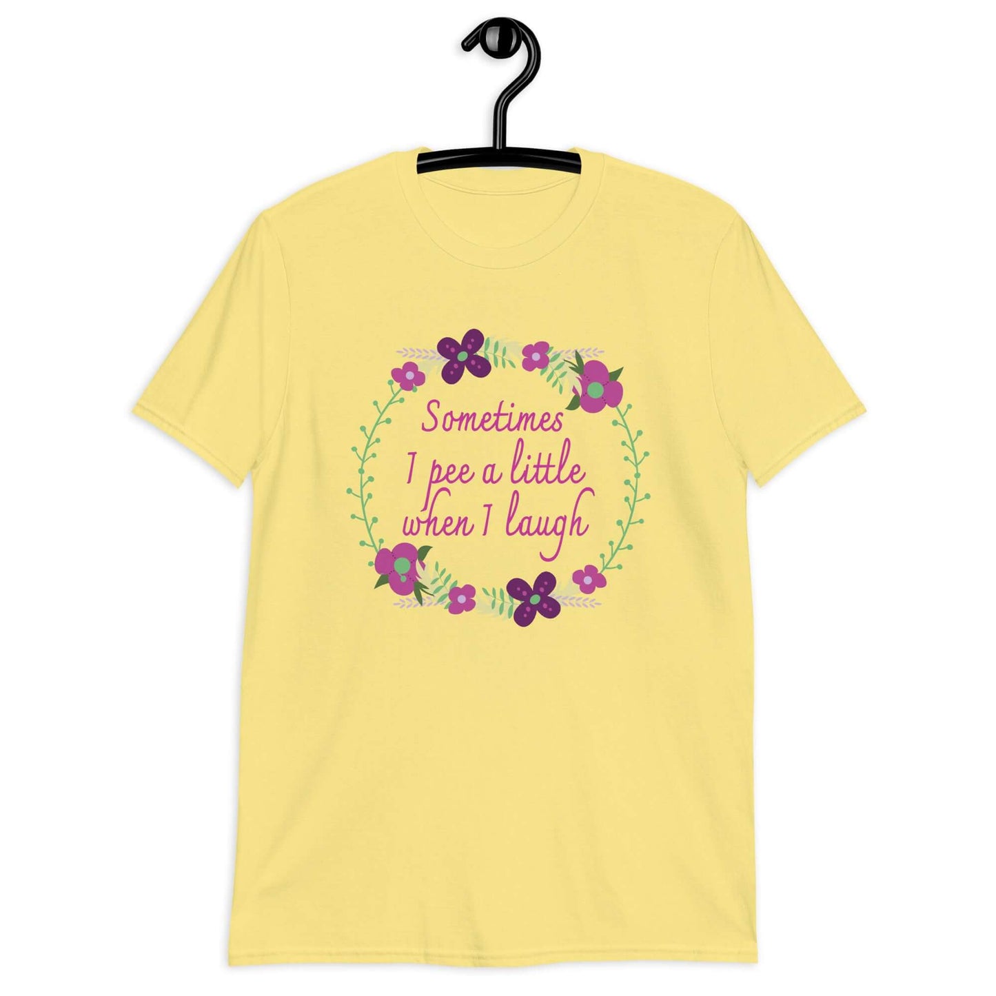 Cornsilk yellow t-shirt that has a minimalistic style line drawing floral wreath with the phrase Sometimes I pee a little when I laugh printed in the center of the wreath. The graphics are printed on the front of the shirt.