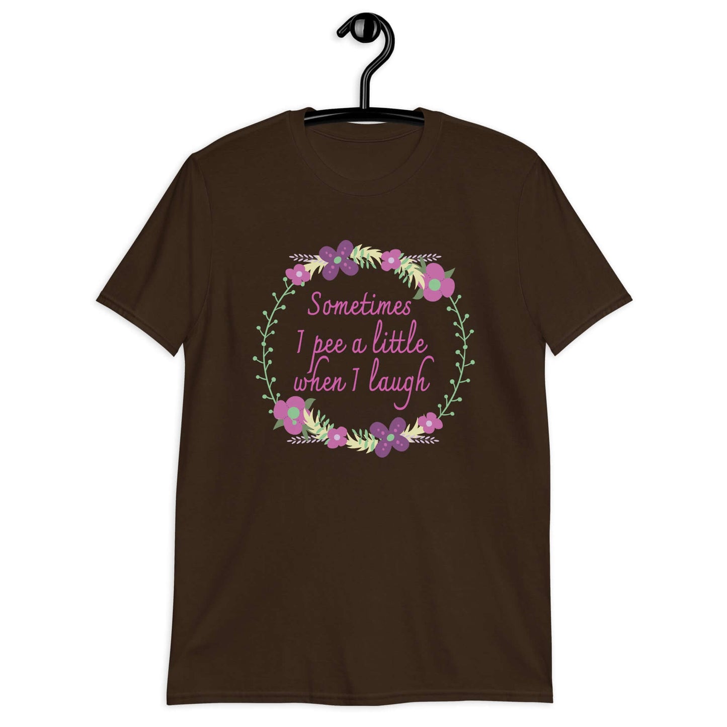 Dark chocolate brown t-shirt that has a minimalistic style line drawing floral wreath with the phrase Sometimes I pee a little when I laugh printed in the center of the wreath. The graphics are printed on the front of the shirt.