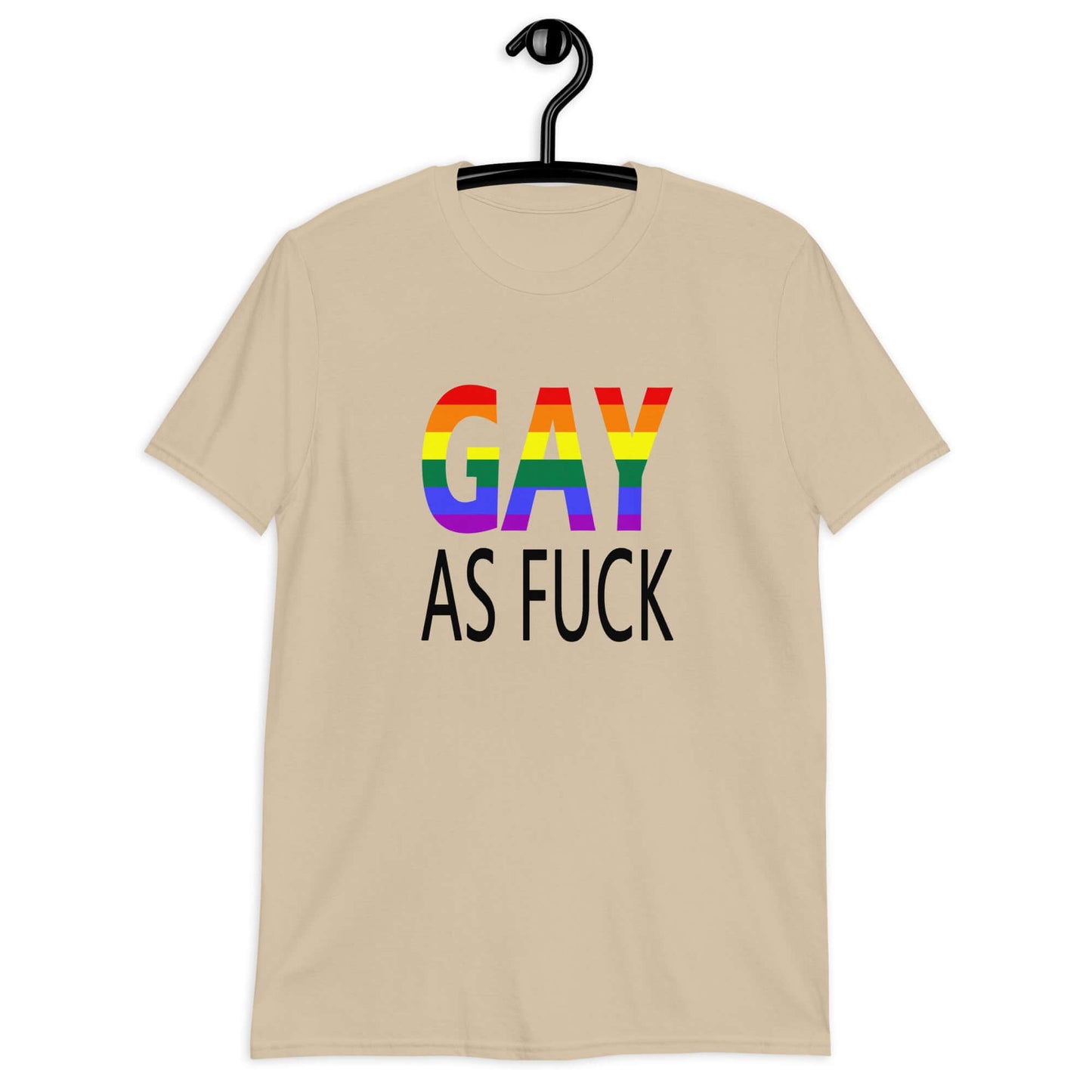 Sand color t-shirt with the words Gay as fuck printed on the front. The word Gay is in rainbow stripe font.