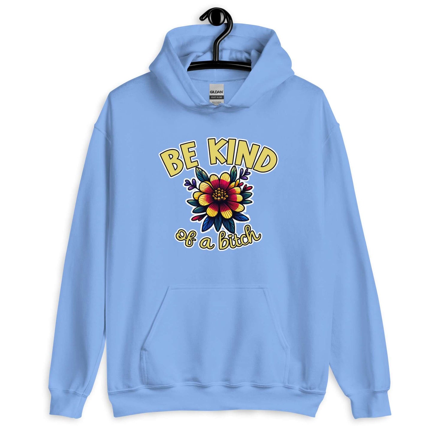 Carolina blue hoodie sweatshirt with an image of a flower and the words Be kind above the flower in yellow bold block font. The words Of a bitch are smaller in script font under the flower. The design is printed on the front of the hoodie.