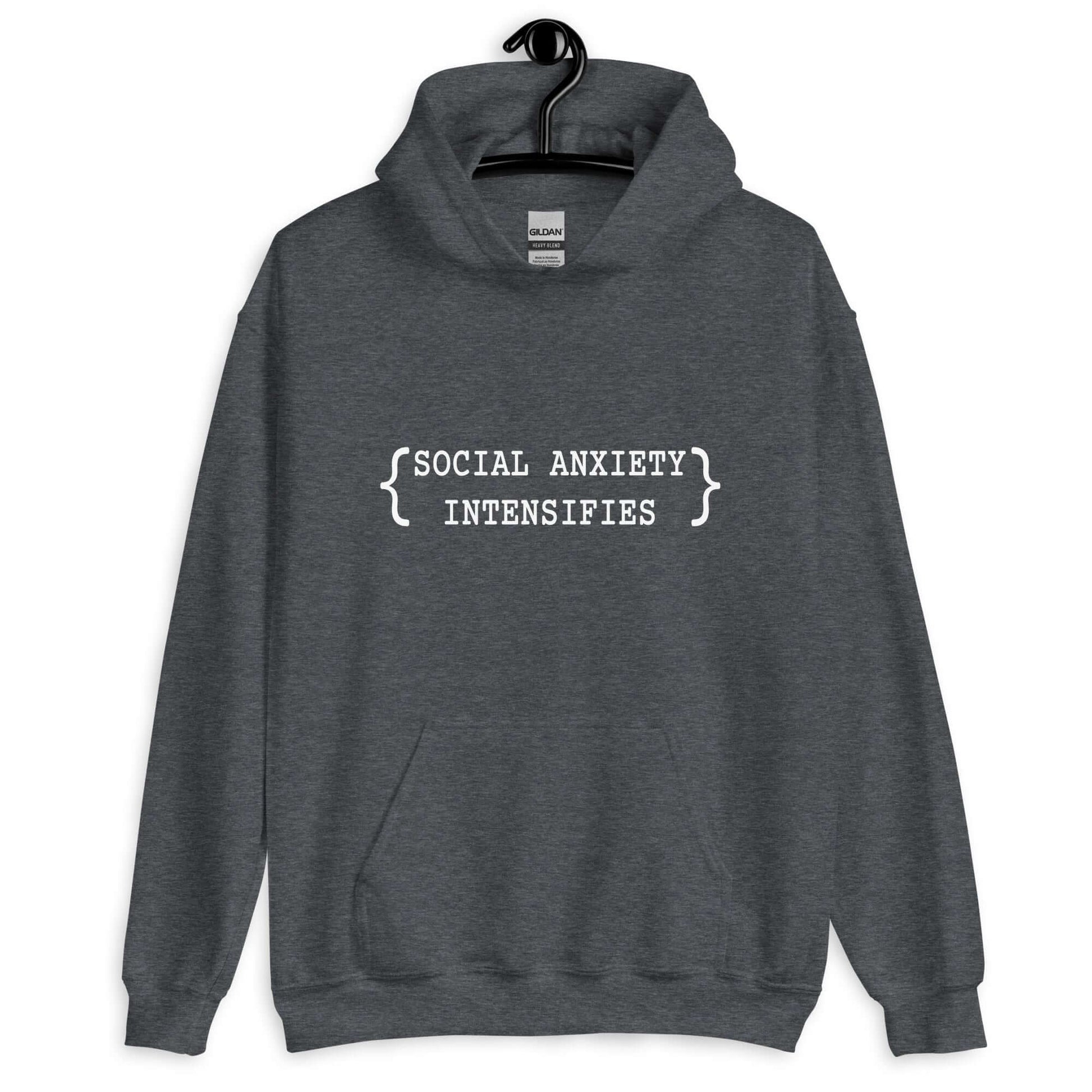 Dark heather grey hoodie sweatshirt with the words Social anxiety intensifies printed on the front.