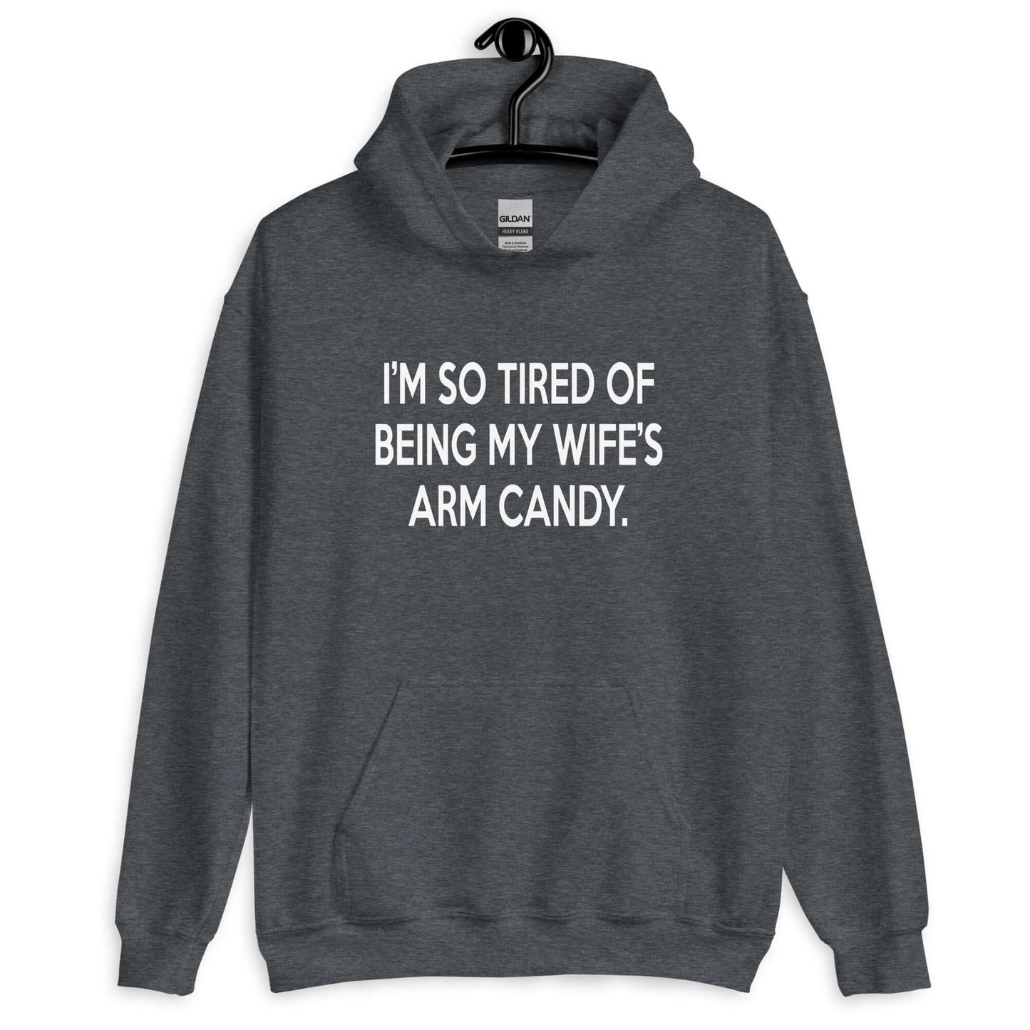 Dark heather hoodie sweatshirt with the funny phrase I'm so tired of being my wife's arm candy printed on the front.