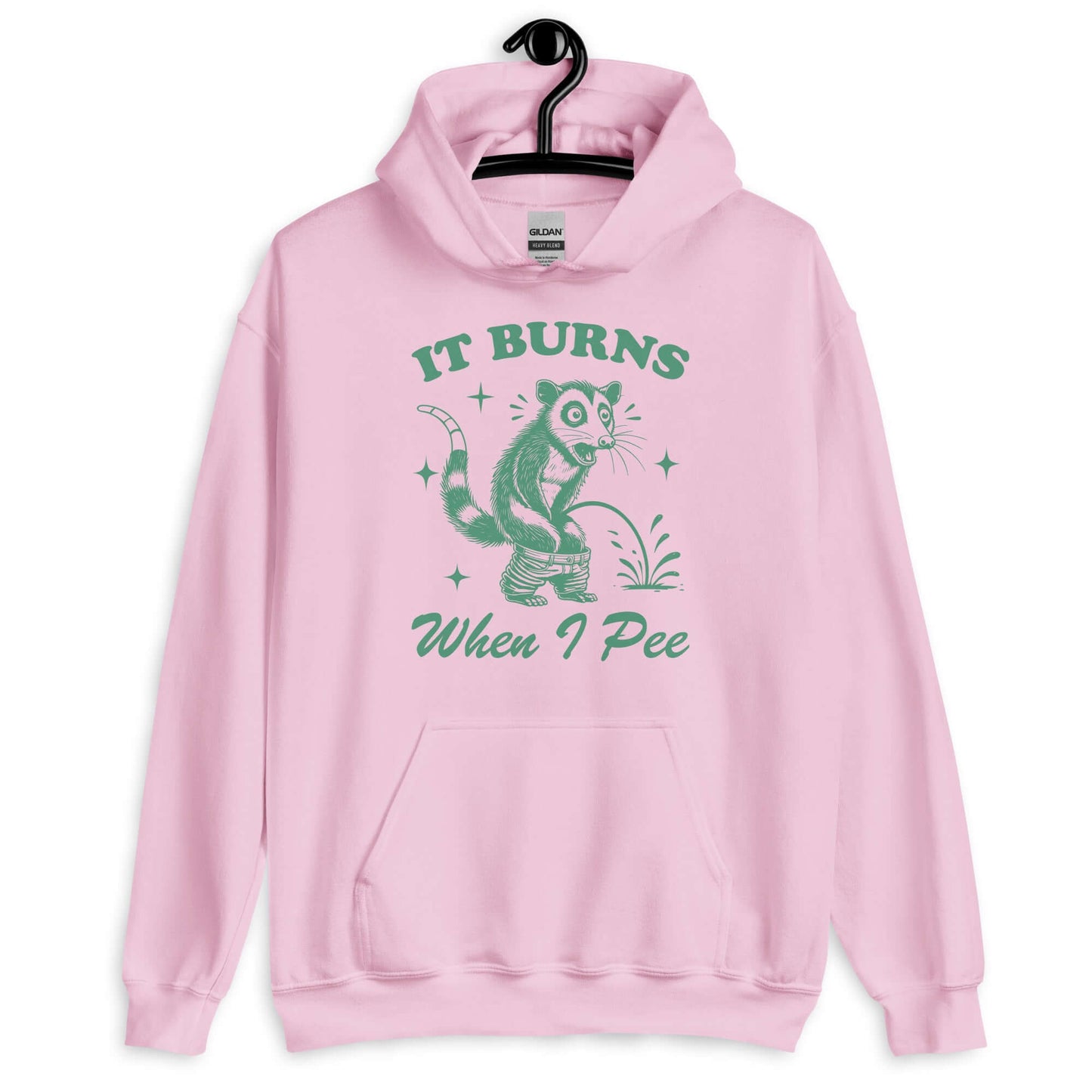 Light pink hoodie sweatshirt that has graphic of an opossum peeing and the words it burns when I pee printed on the front.
