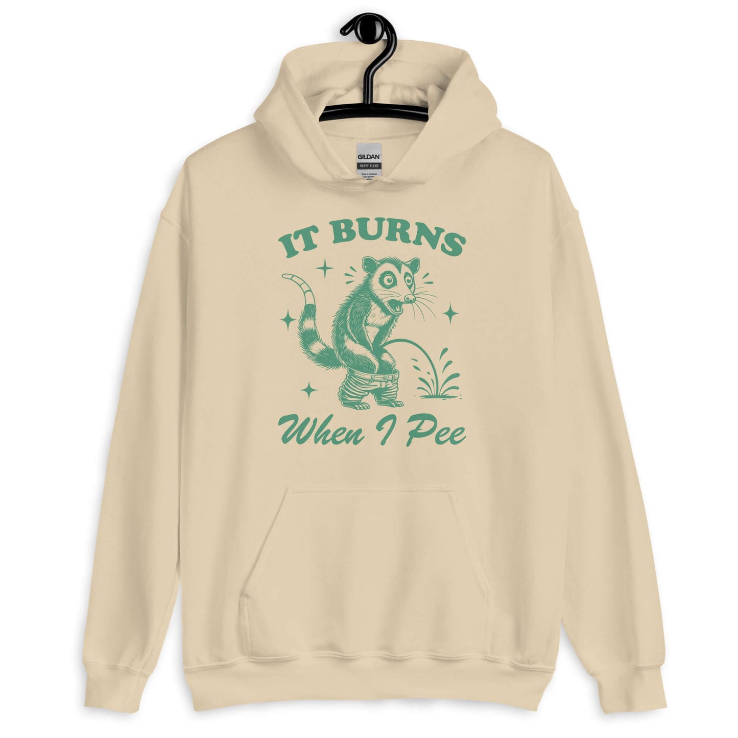 Sand color hoodie sweatshirt that has graphic of an opossum peeing and the words it burns when I pee printed on the front.