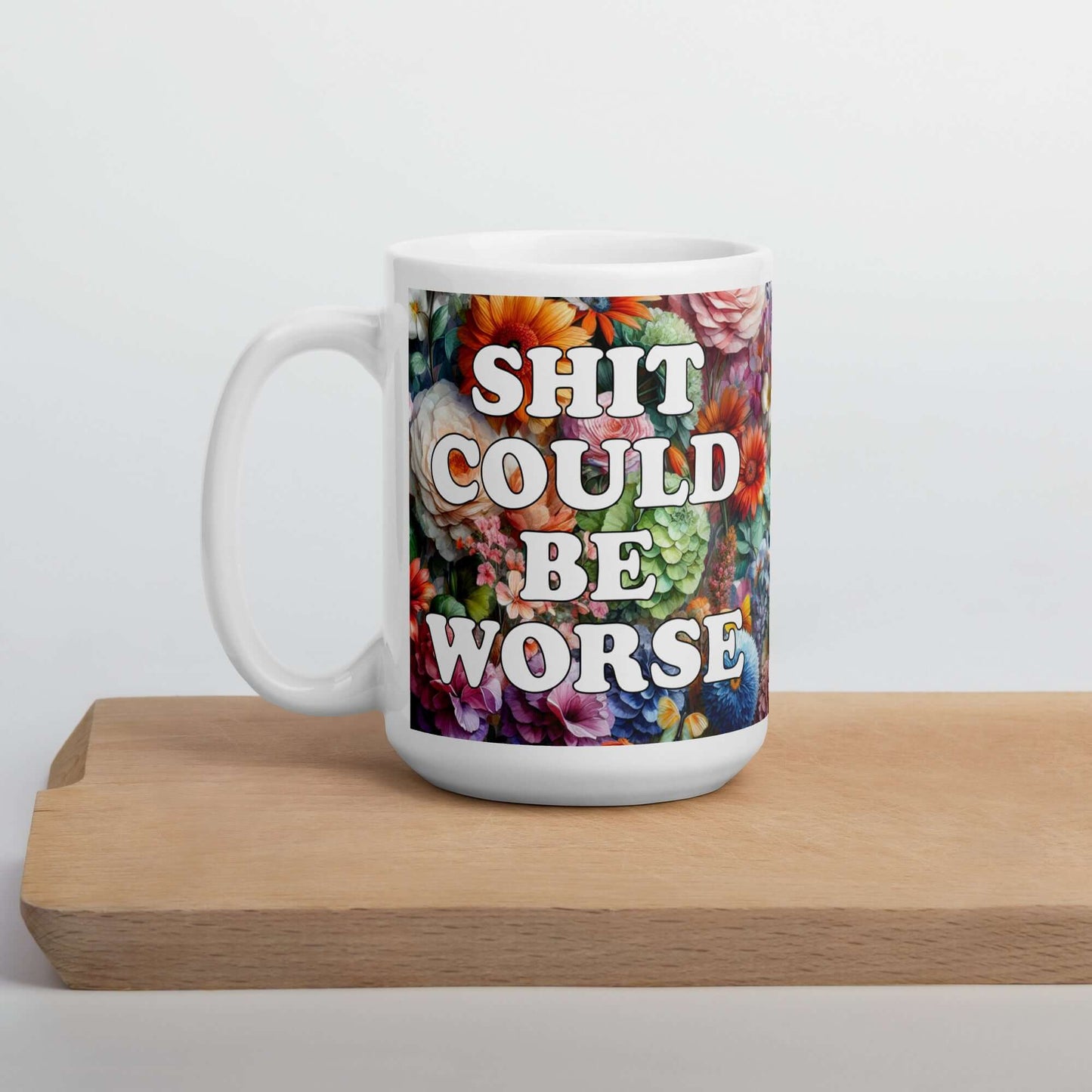 White ceramic mug floral background and the words Shit could be worse printed on both sides.