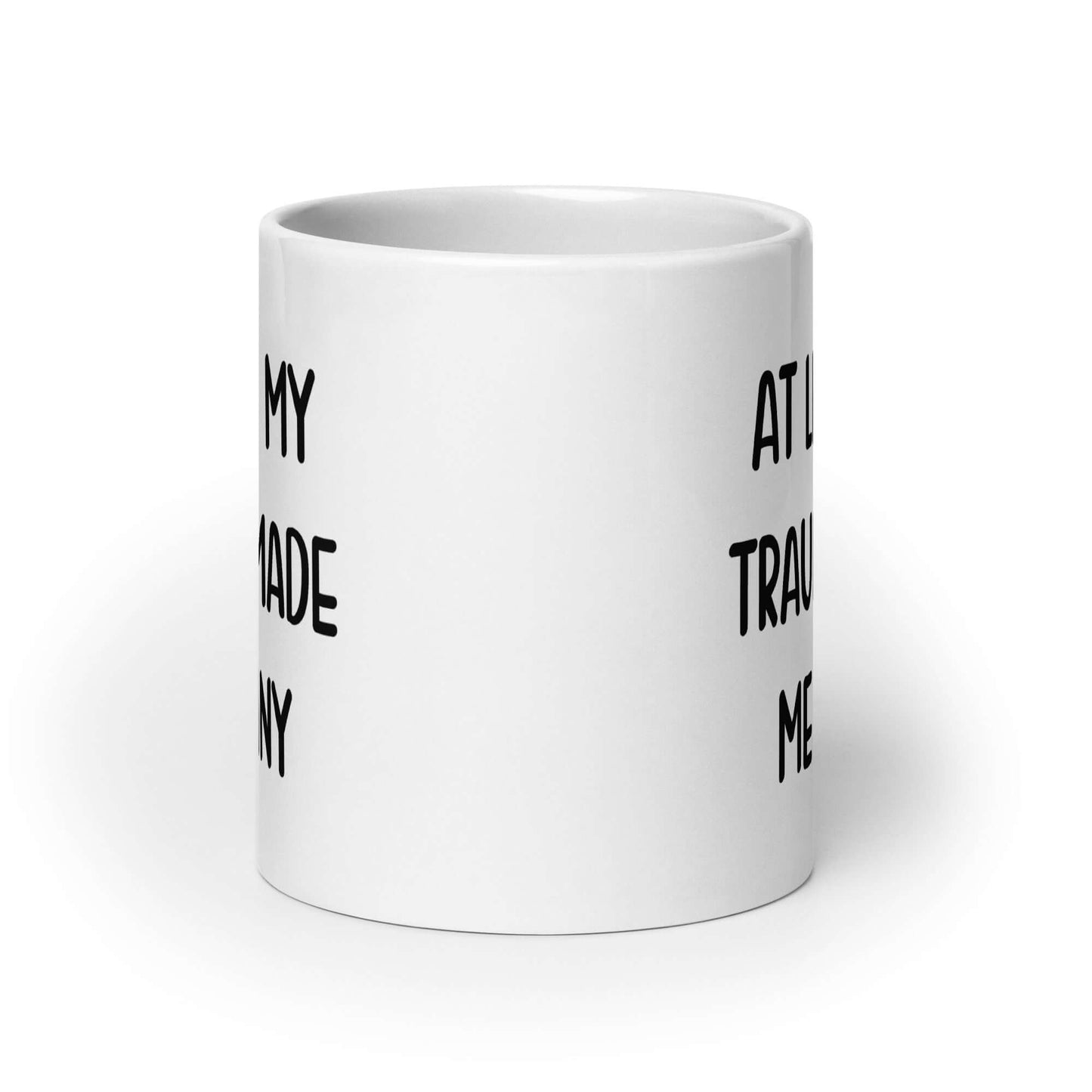 White ceramic mug with the words At least my trauma made me funny printed on both sides.