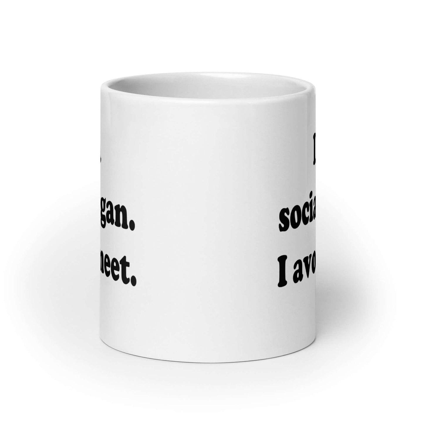 White ceramic coffee mug with the pun phrase I'm a social vegan, I avoid meet printed on both sides.
