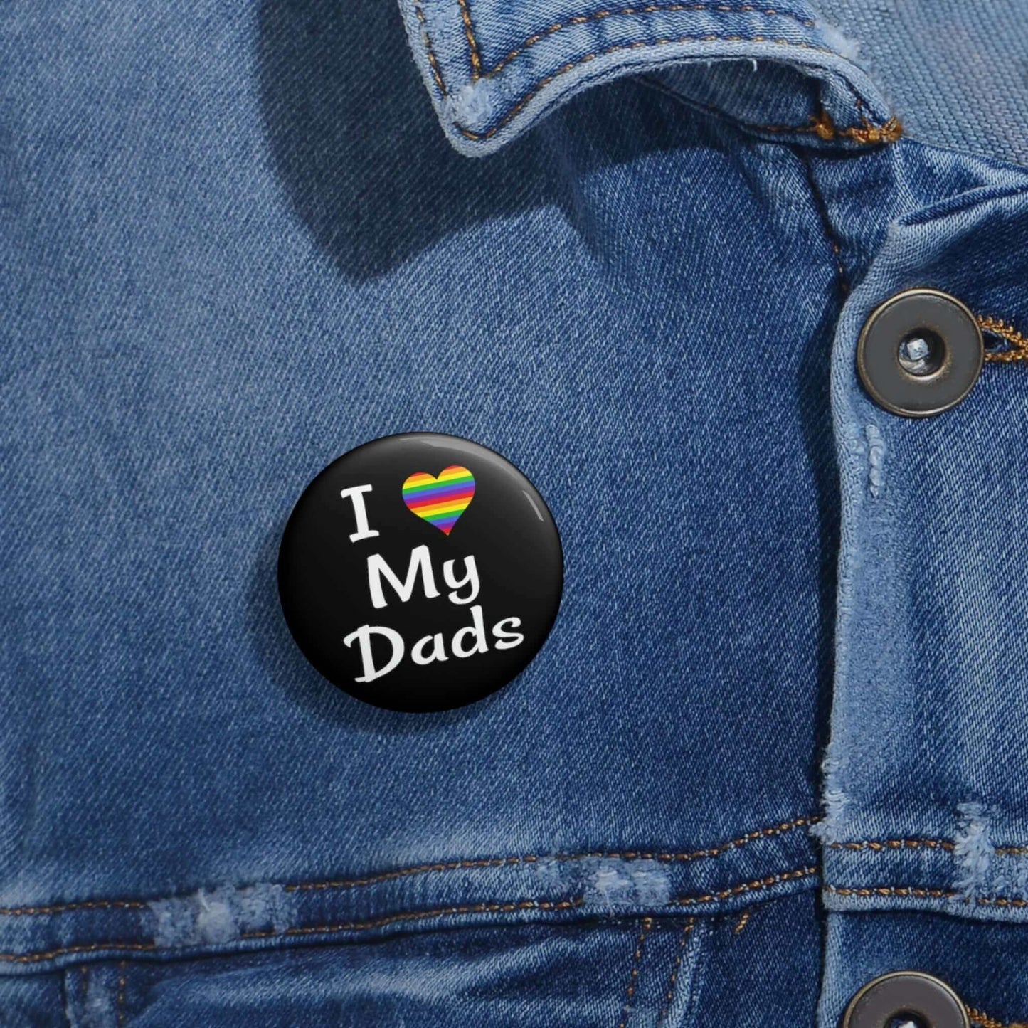 Black pin-back button that says I heart my dads. The heart is rainbow.