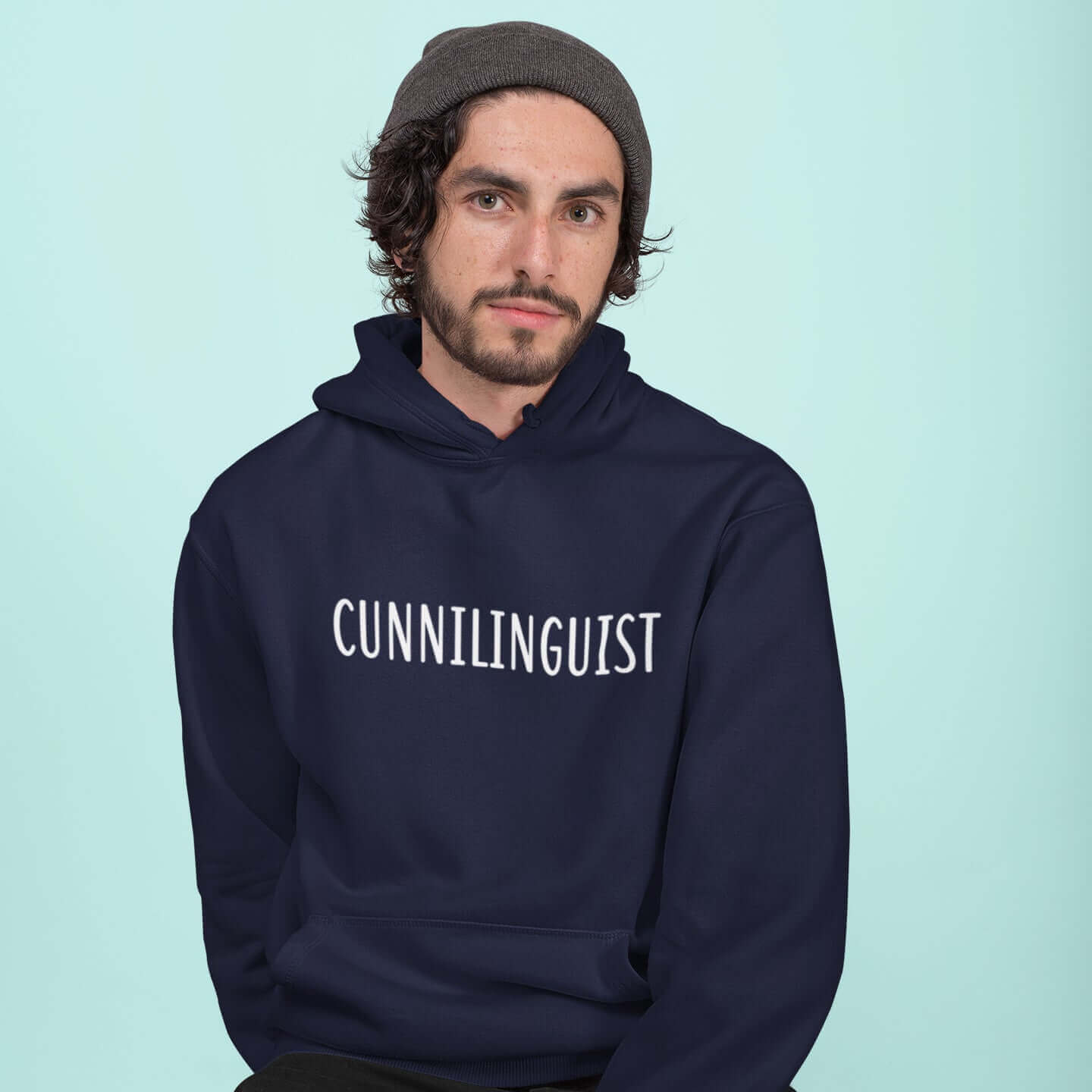 Man wearing a navy blue hoodie sweatshirt with the word Cunnilinguist printed on the front.