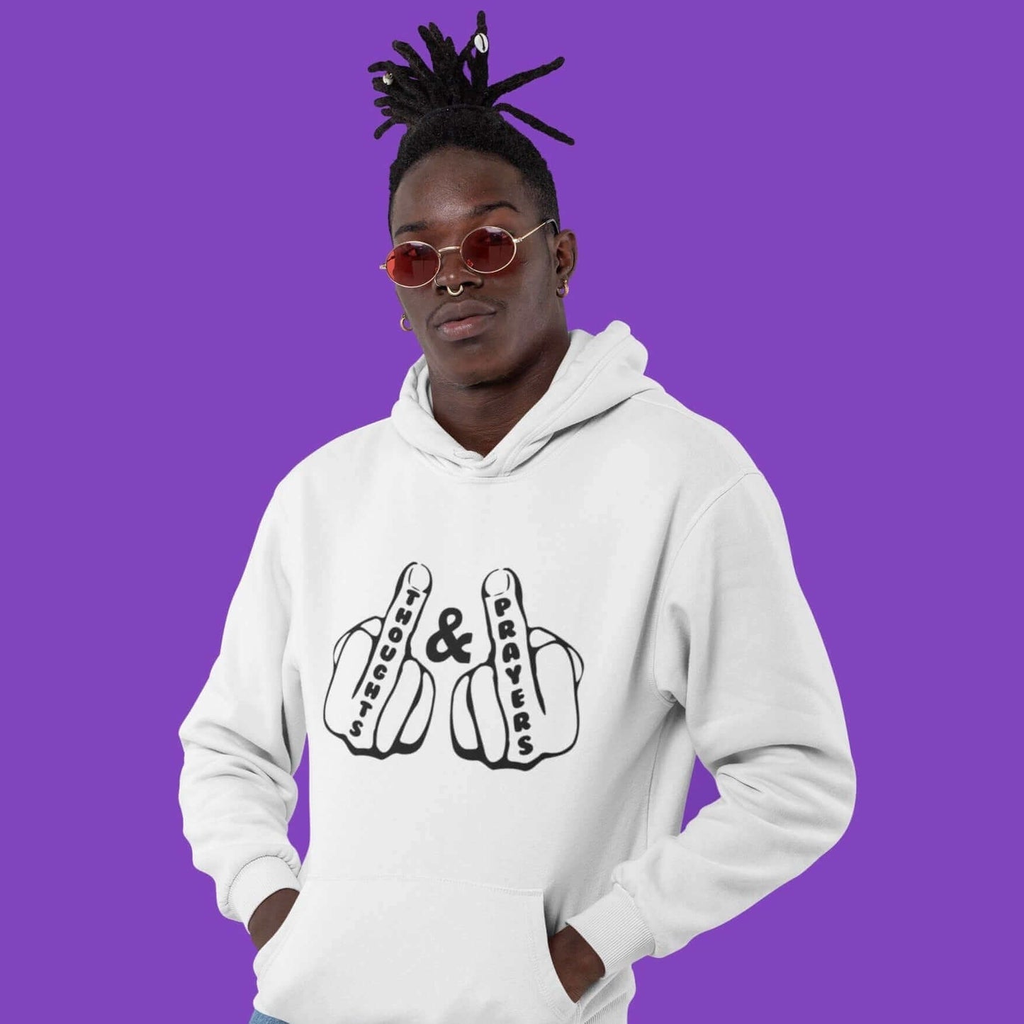 Man wearing a white hoodie sweatshirt with an image of 2 line drawing hands with the middle fingers up. The word Thoughts is printed on one middle finger and the word Prayers is printed on the other middle finger. The graphics are printed on the front of