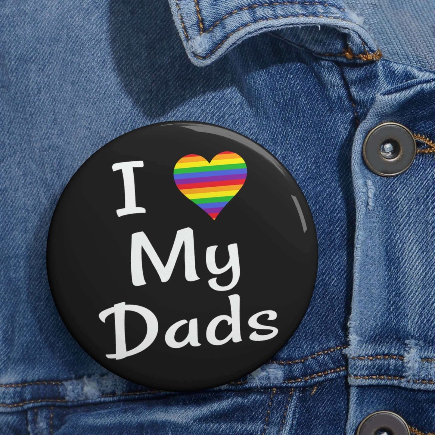 Black pin-back button that says I heart my dads. The heart is rainbow.