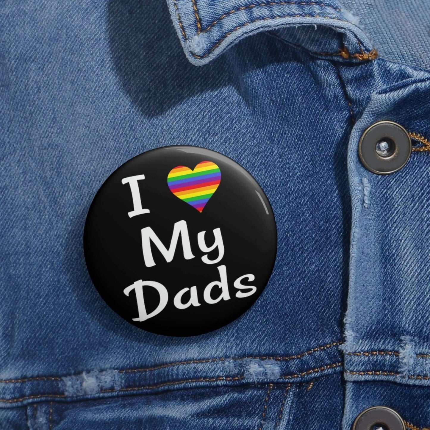 Black pin-back button that says I heart my dads. The heart is rainbow.