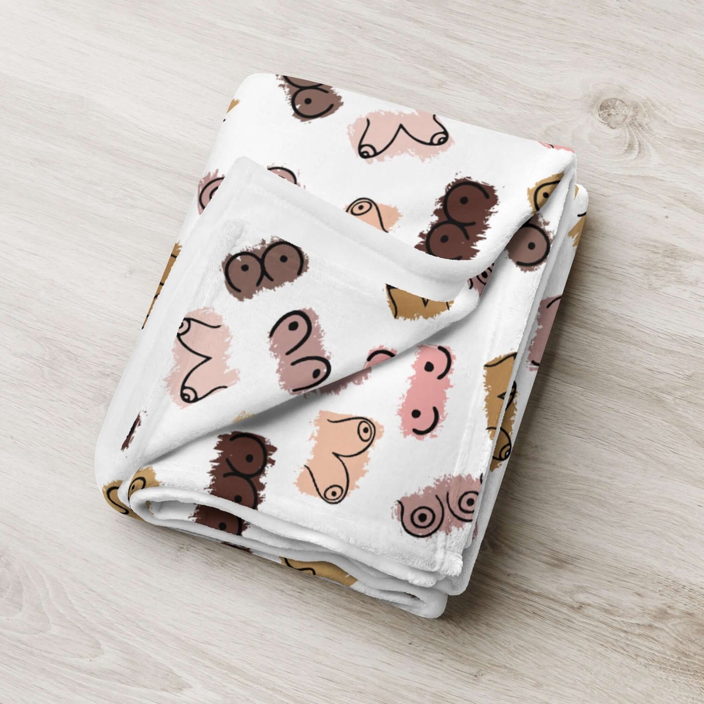 White fleece throw blanket with drawings of breasts in various skin tones printed all over.