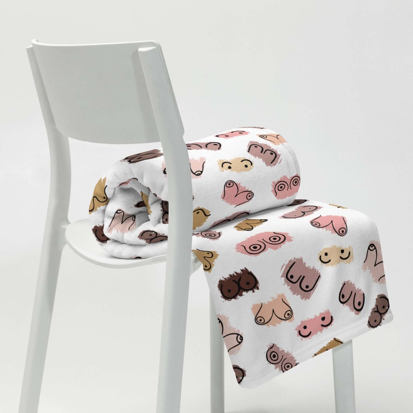 White fleece throw blanket with drawings of breasts in various skin tones printed all over.