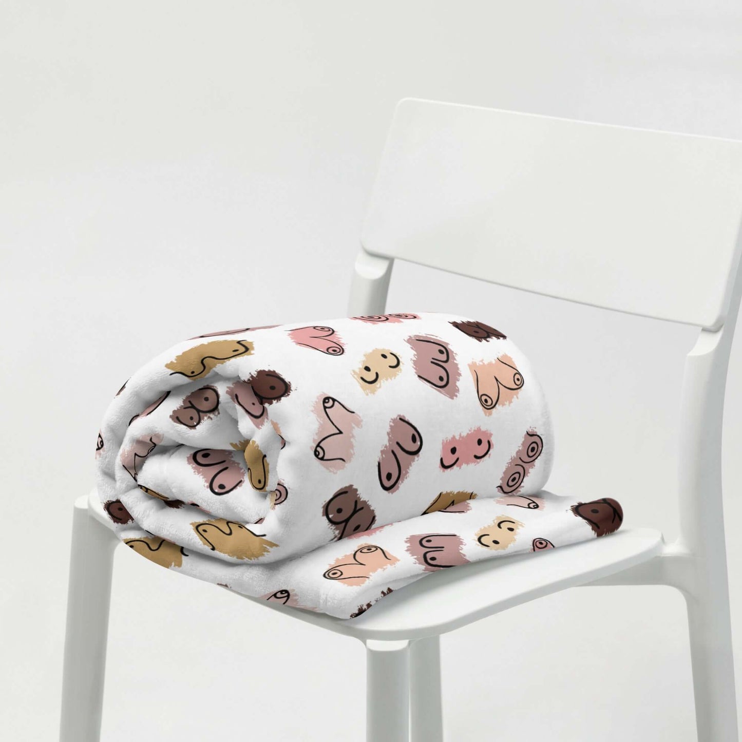 White fleece throw blanket with drawings of breasts in various skin tones printed all over.