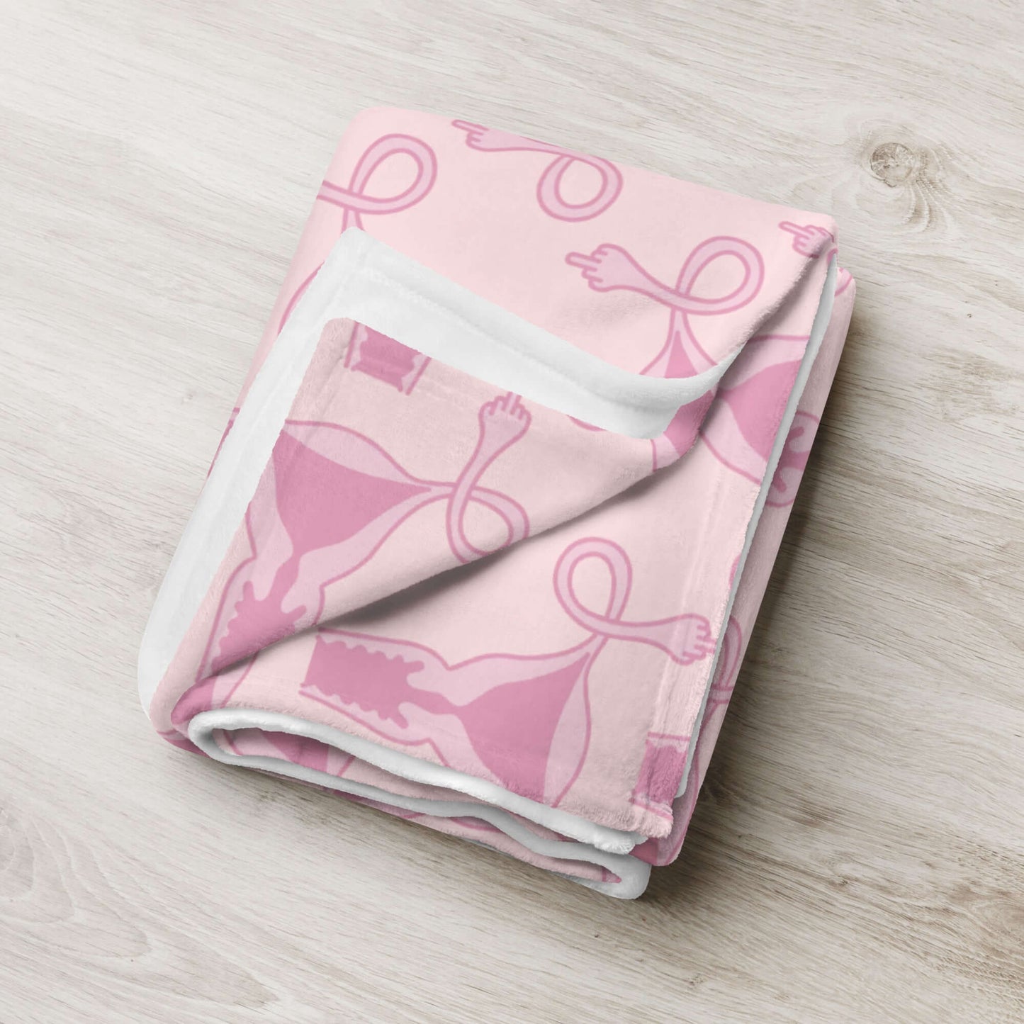 Folded Pink fleece throw blanket with pink uterus flipping middle finger graphic printed all over.