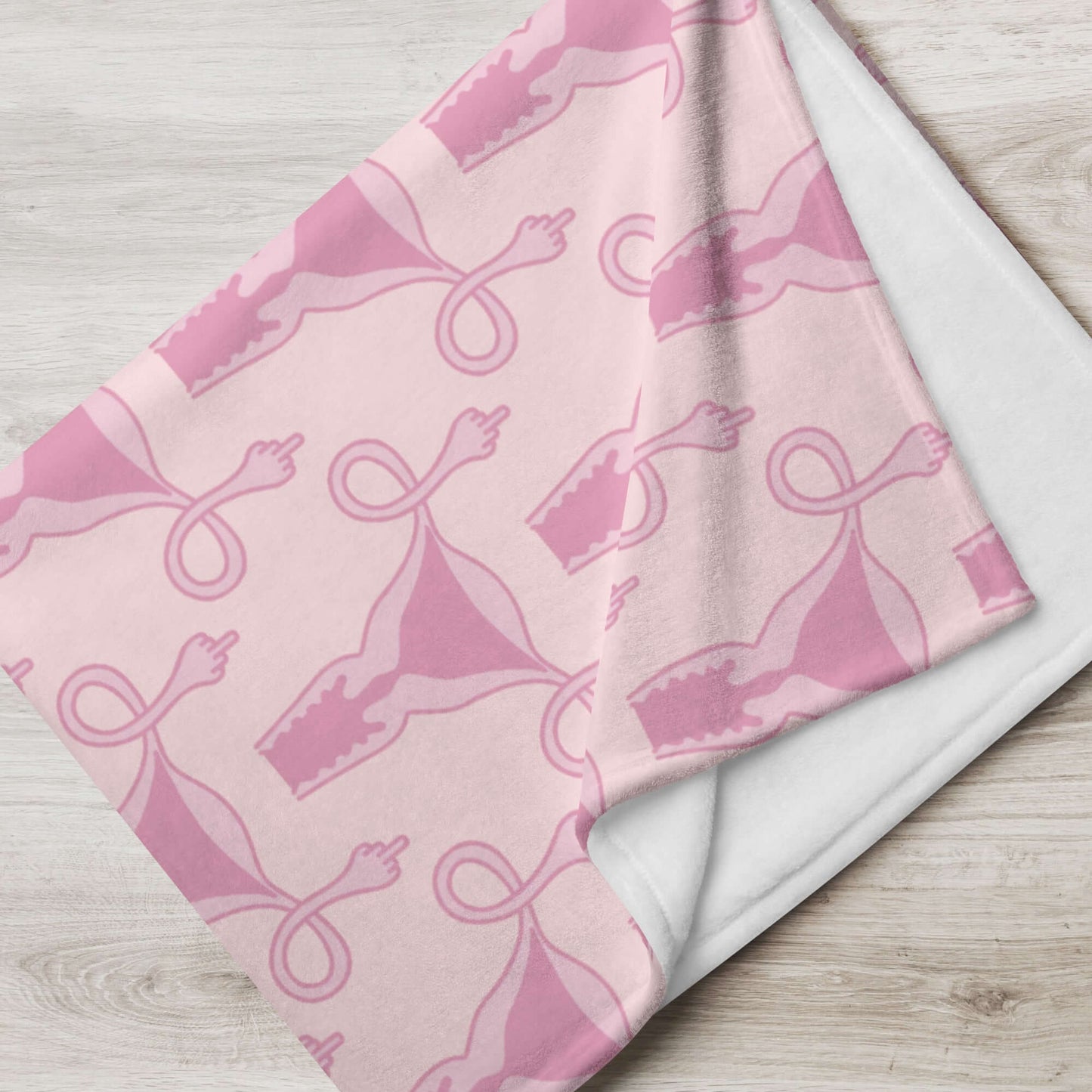 Folded pink fleece throw blanket with pink uterus flipping middle finger graphic printed all over.