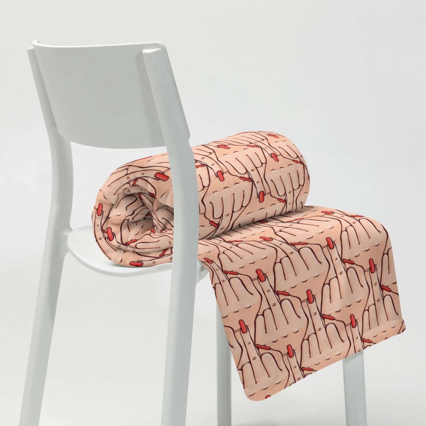 Folded throw blanket with graphic of Caucasian womans hand flipping the middle finger. The finger has a long red fingernail. The graphic is overlapping and printed all over.