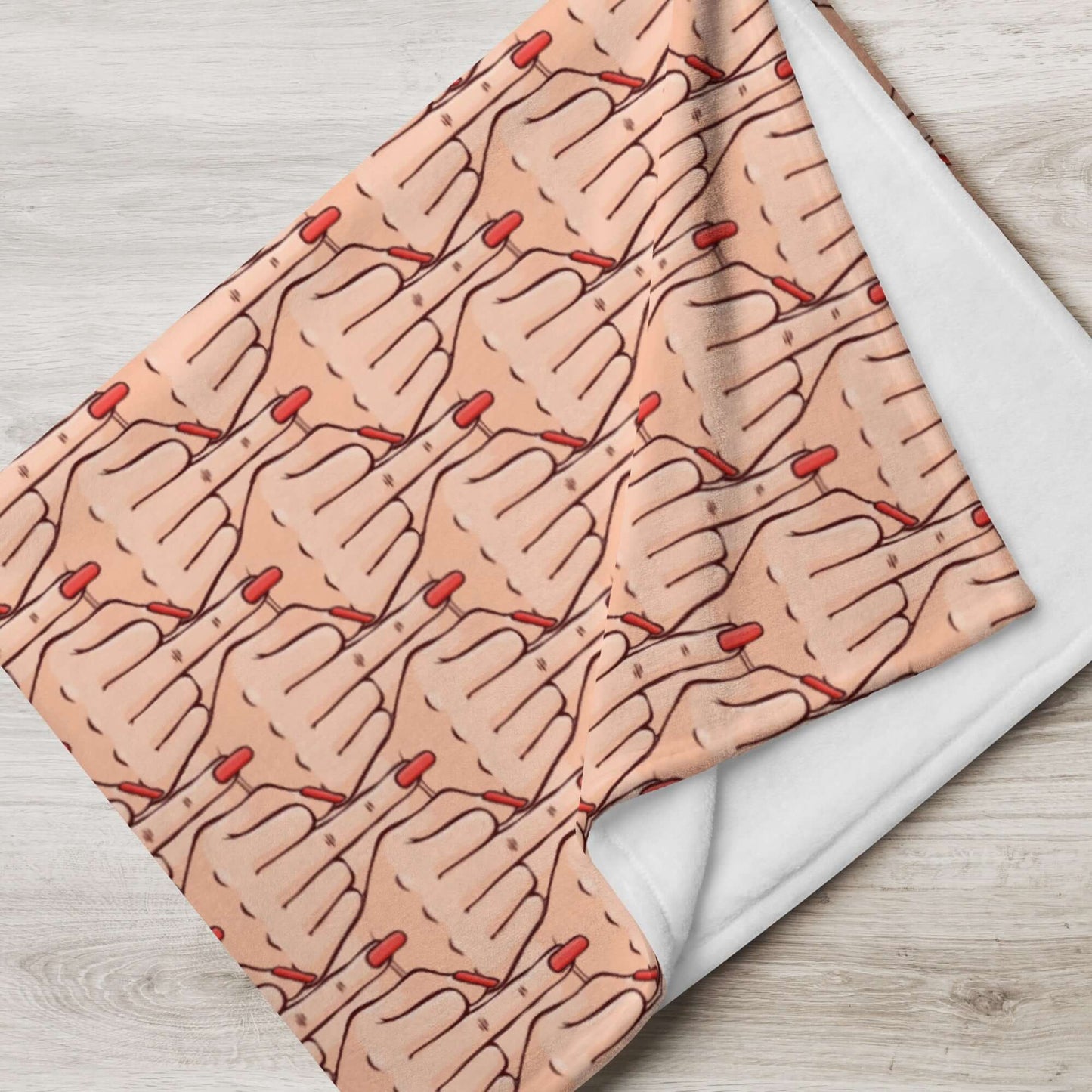 Folded throw blanket with graphic of Caucasian womans hand flipping the middle finger. The finger has a long red fingernail. The graphic is overlapping and printed all over.
