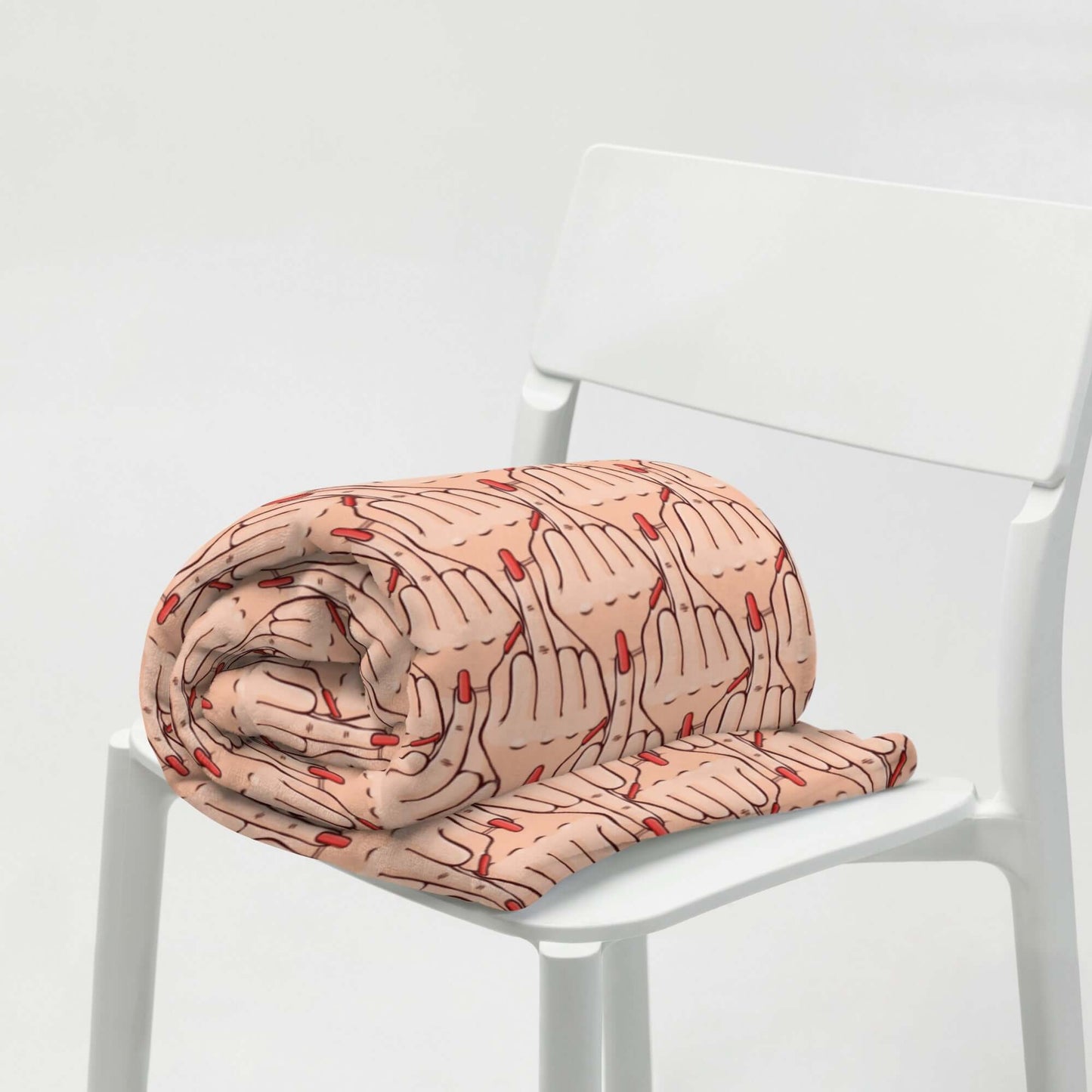 Folded throw blanket with graphic of Caucasian womans hand flipping the middle finger. The finger has a long red fingernail. The graphic is overlapping and printed all over.