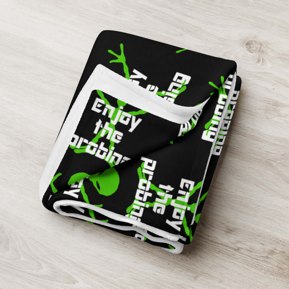 Black fleece throw blanket with an image of an alien and the funny phrase Enjoy the probing printed all over the blanket.