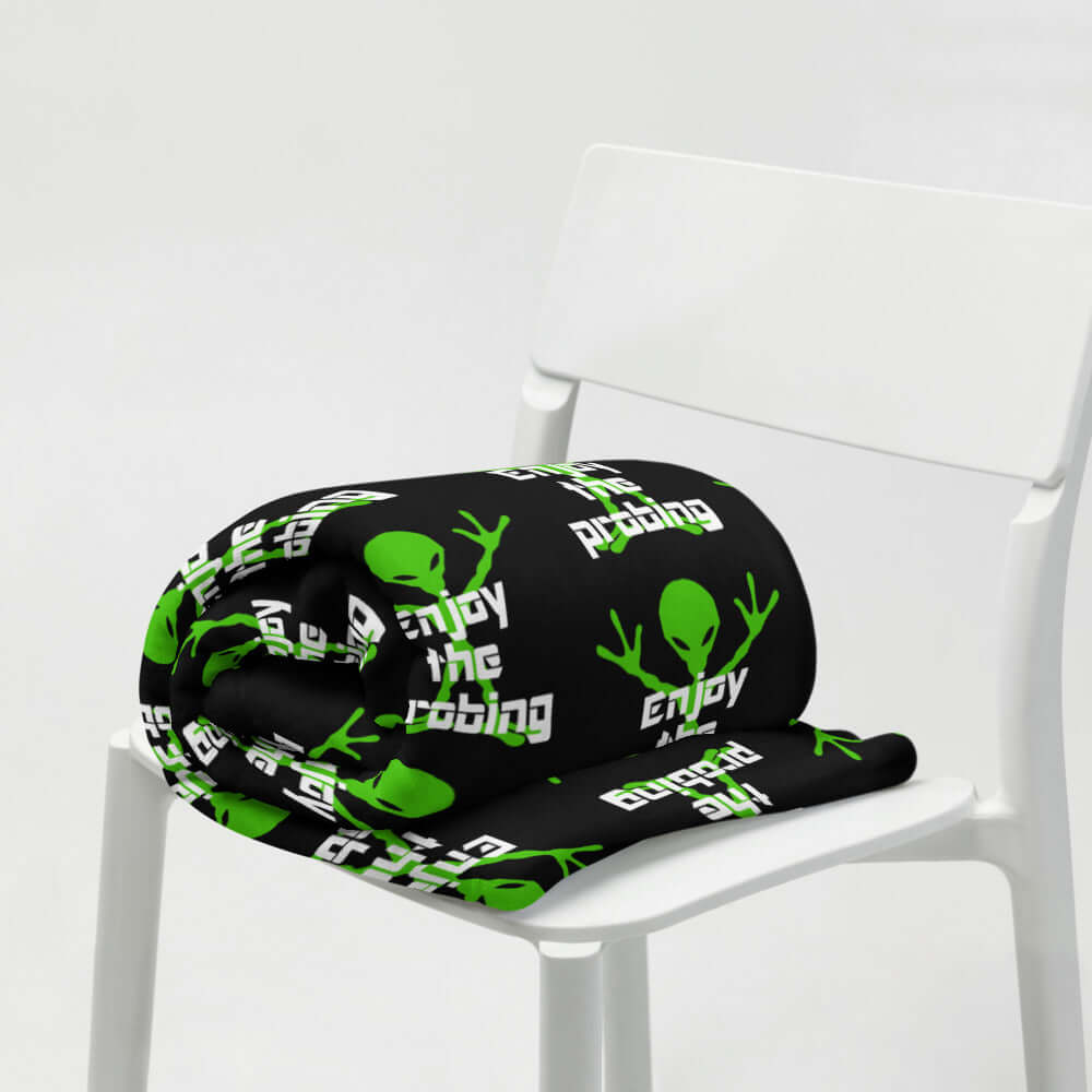 Black fleece throw blanket with an image of an alien and the funny phrase Enjoy the probing printed all over the blanket.