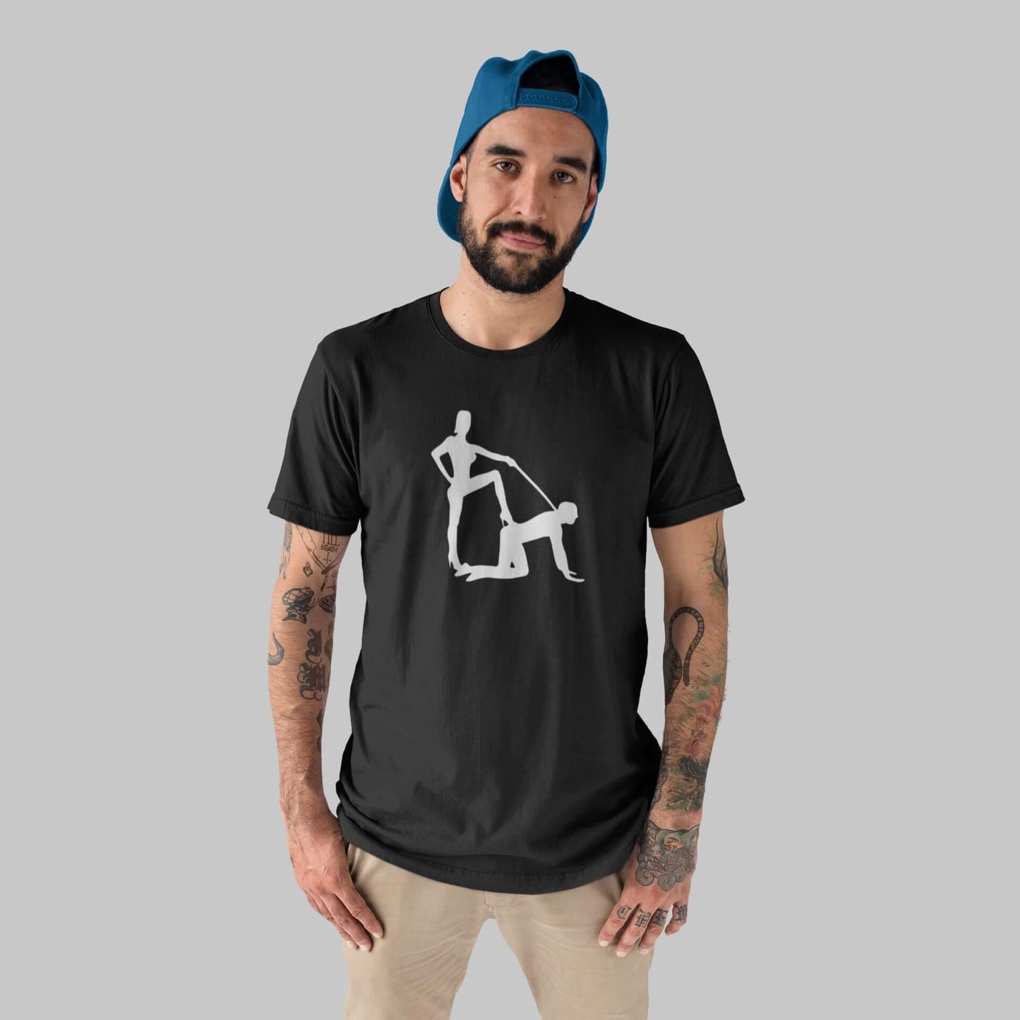 Man wearing a black t-shirt with the image of a silhouette of a man on his hands and knees and a dominatrix holding his leash printed on the front.