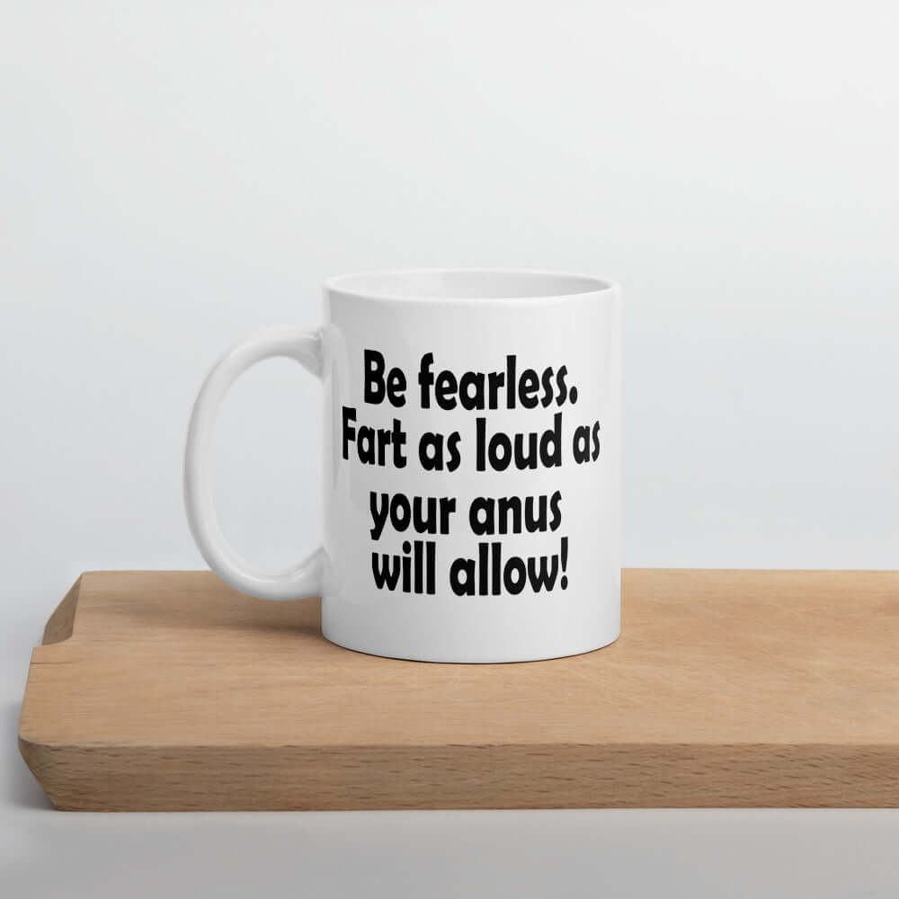 White ceramic coffee mug with the phrase Be fearless. Fart as loud as your anus will allow printed on both sides.
