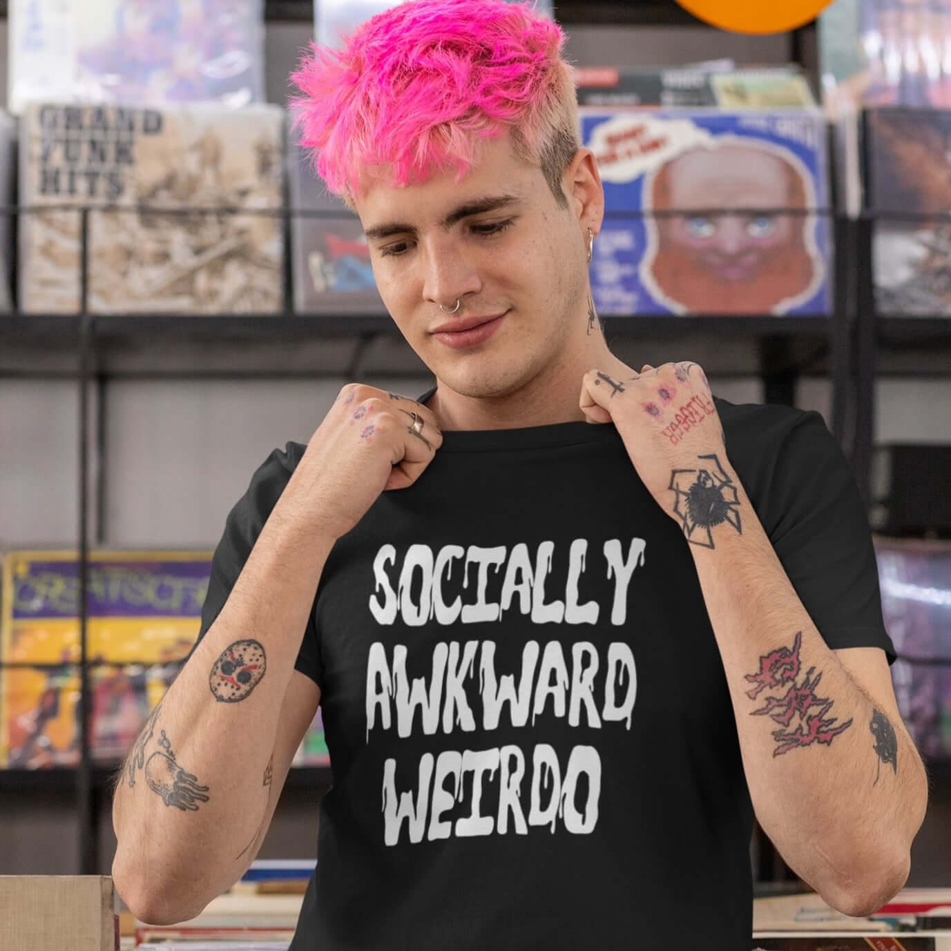 Man with bright pink hair wearing black t-shirt that says socially awkward weirdo on the front.