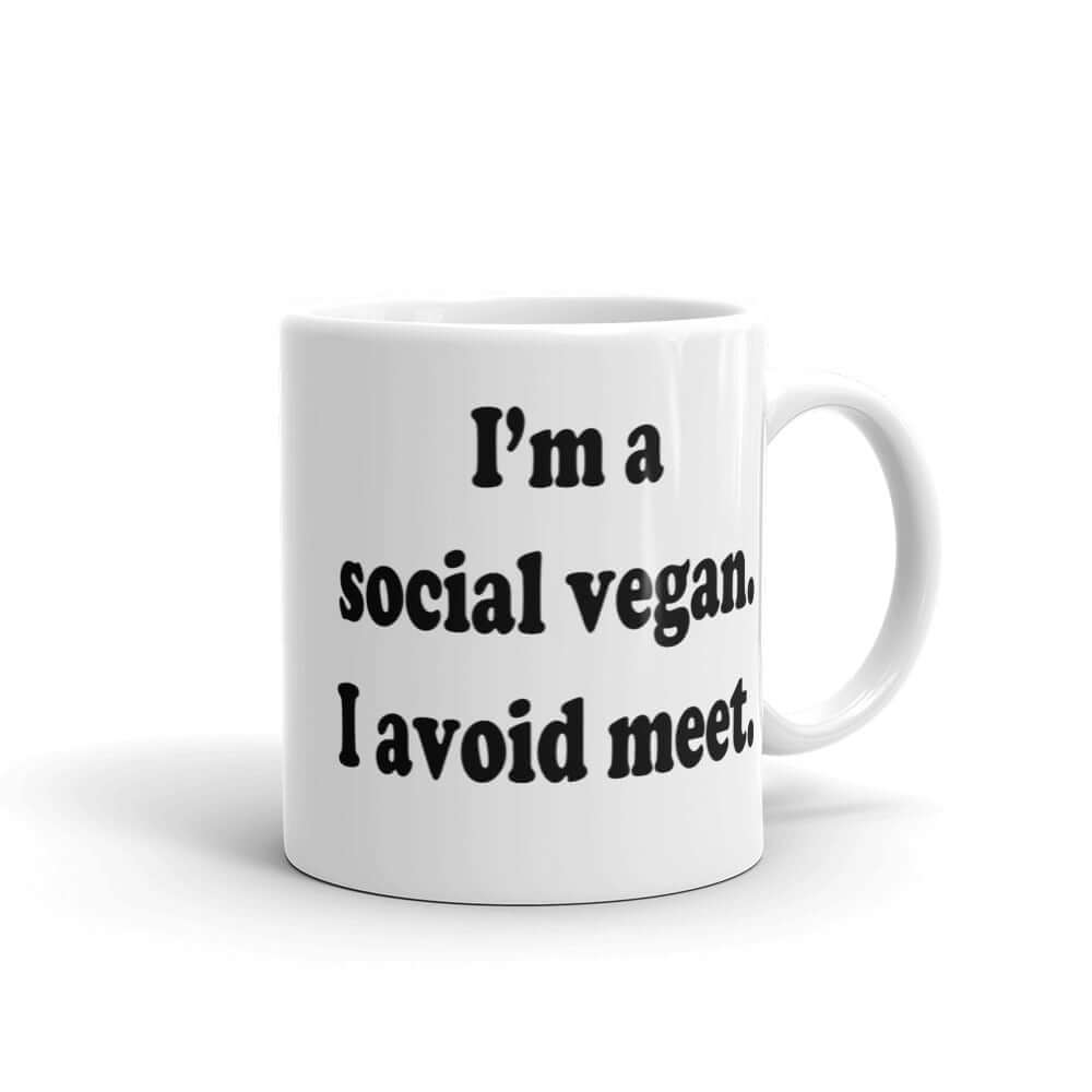 White ceramic coffee mug with the pun phrase I'm a social vegan, I avoid meet printed on both sides.