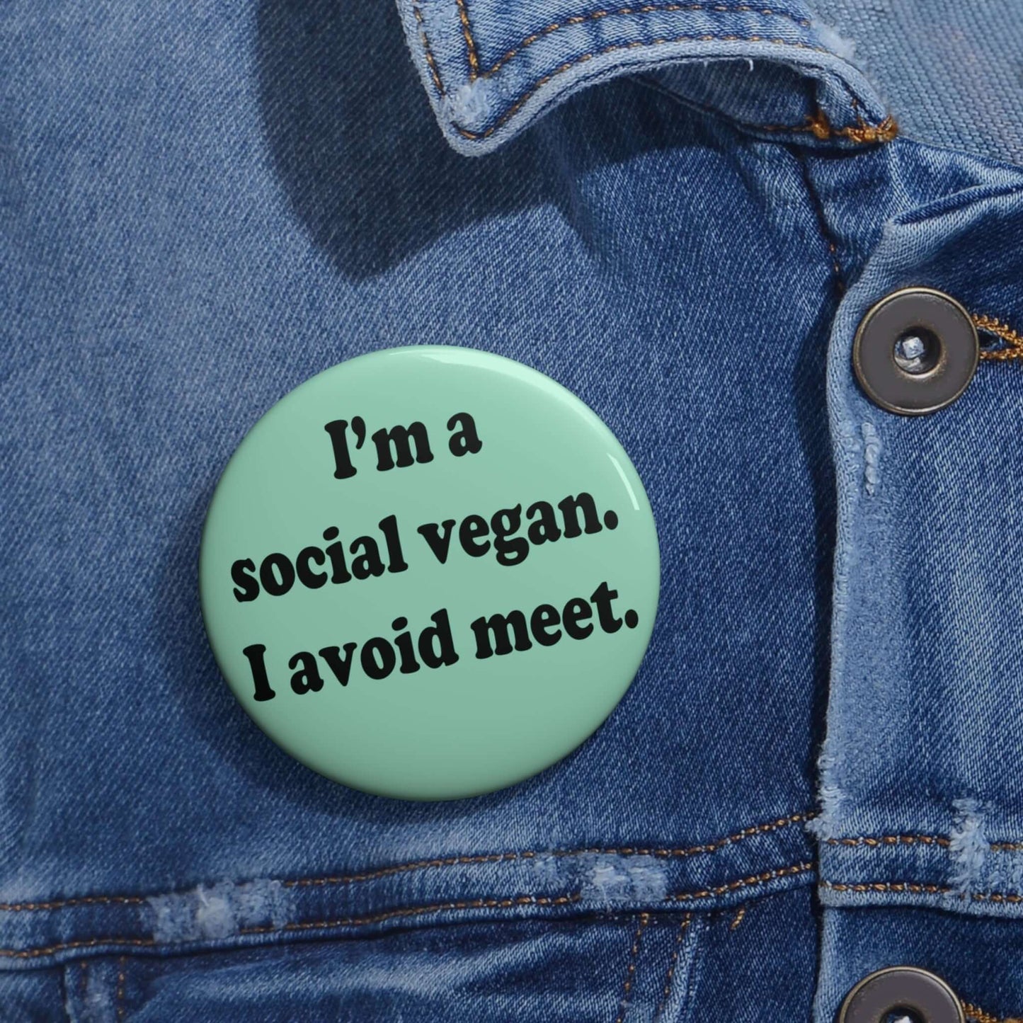 Mint green pinback button that says Im a social vegan, I avoid meet. Meet is spelled M E E T instead of M E A T.