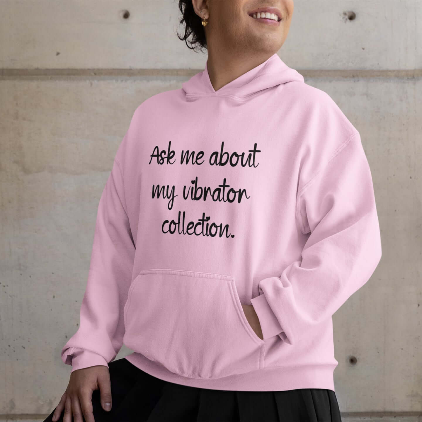 Person wearing a light pink hoodie sweatshirt with the phrase Ask me about my vibrator collection printed on the front.