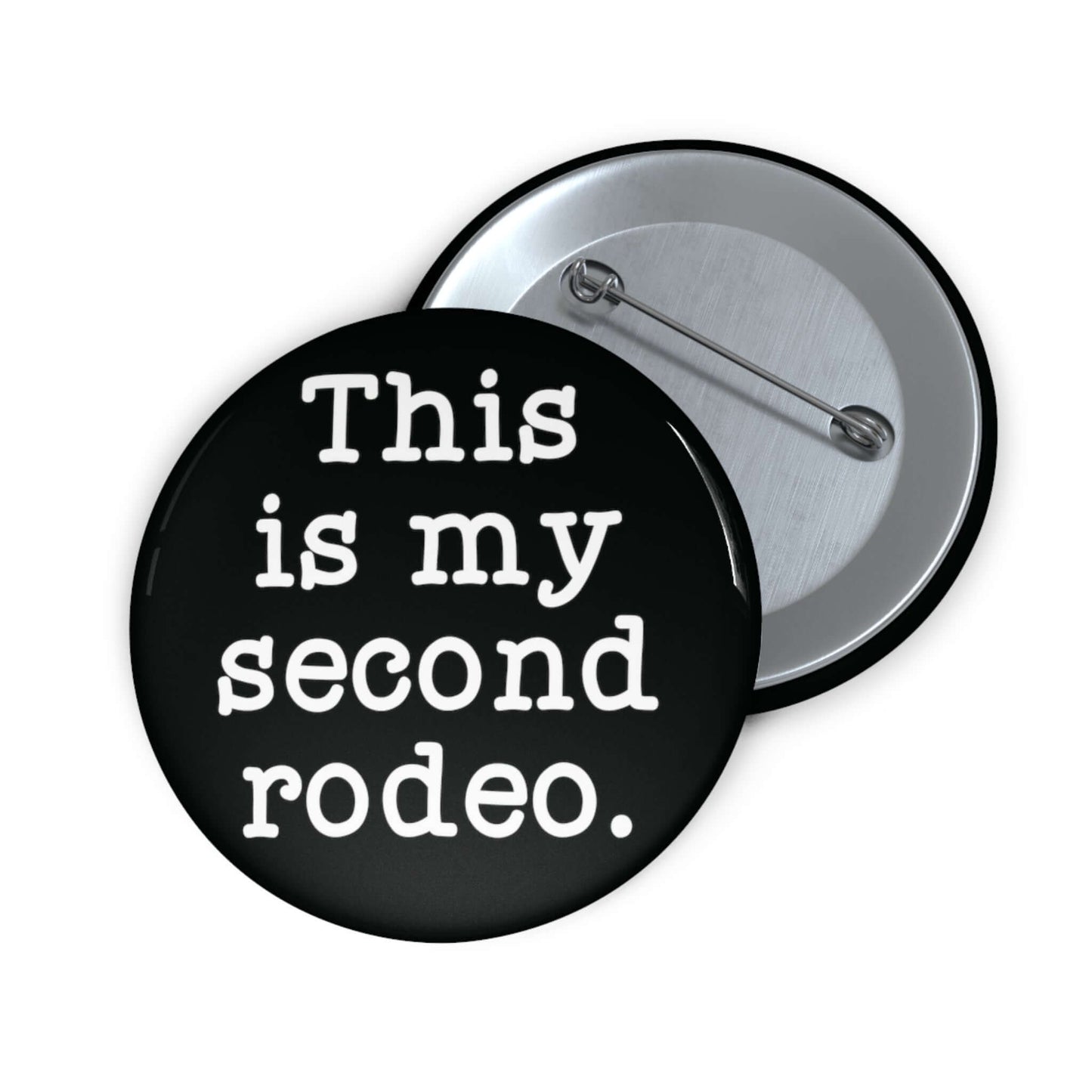 Black pin-back button with the phrase This is my second rodeo printed on it in white.