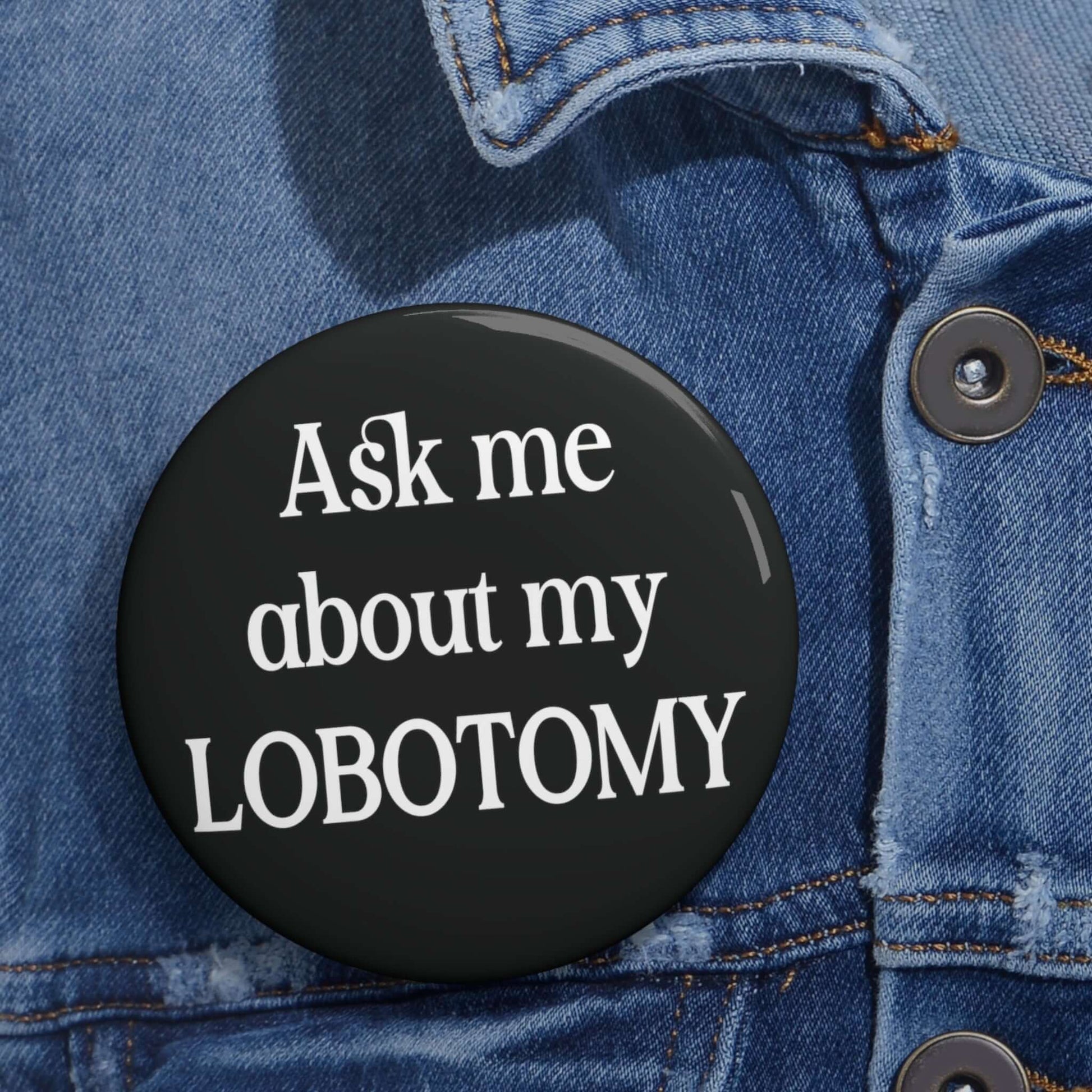 Black pin-back button with the phrase Ask me about my lobotomy printed on it.