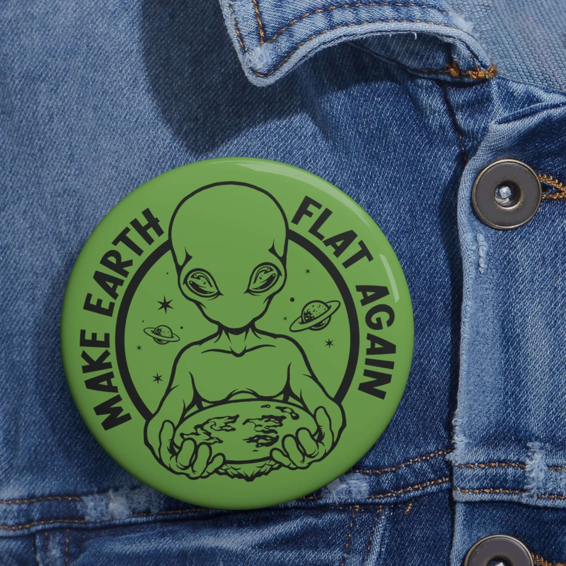 Green pinback button with an image of an alien holding flat earth and the words Make earth flat again.