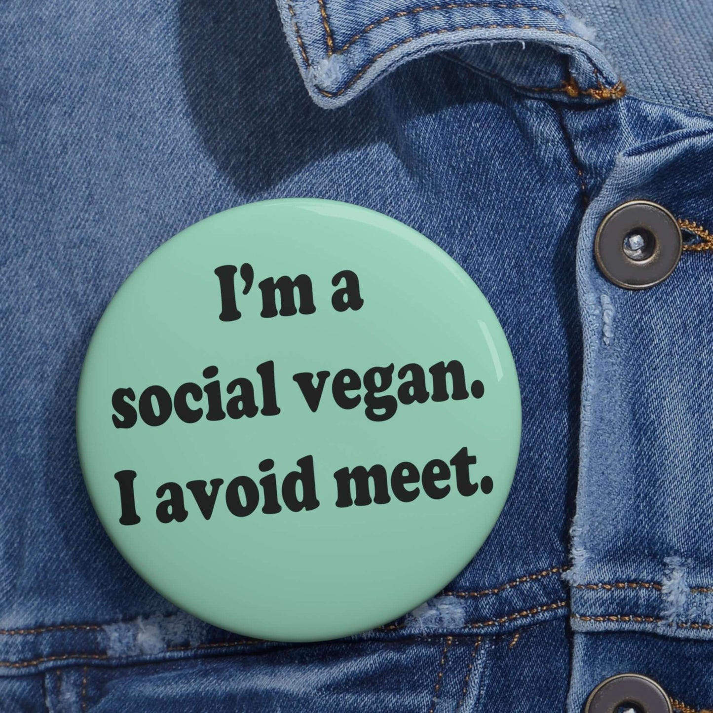 Mint green pinback button that says Im a social vegan, I avoid meet. Meet is spelled M E E T instead of M E A T.