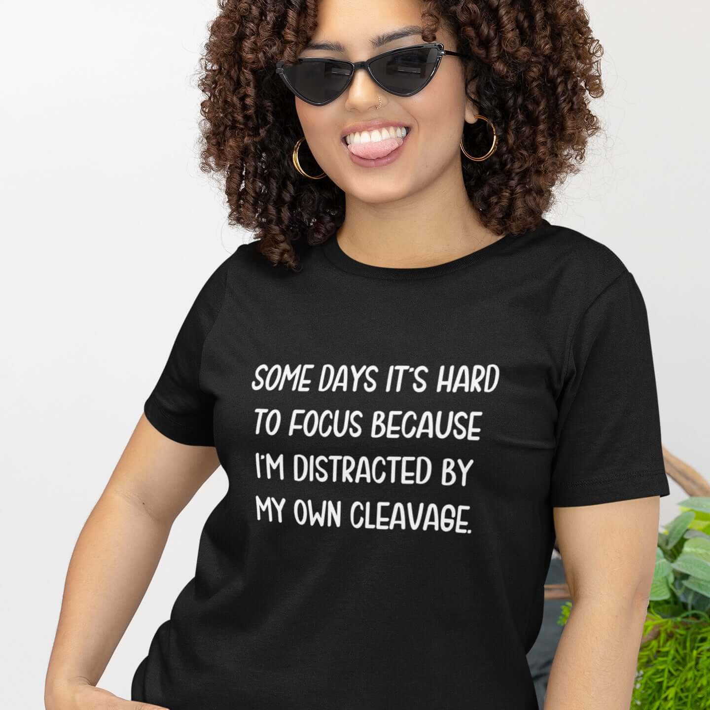 Woman wearing a black t-shirt with the phrase Some days it's hard to focus because I'm distracted by my own cleavage printed on the front.