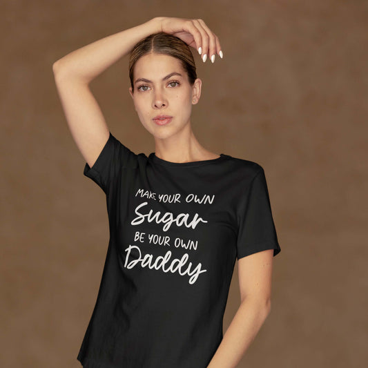 Woman posing wearing a black t-shirt with the phrase Make your own sugar Be your own Daddy printed on the front.